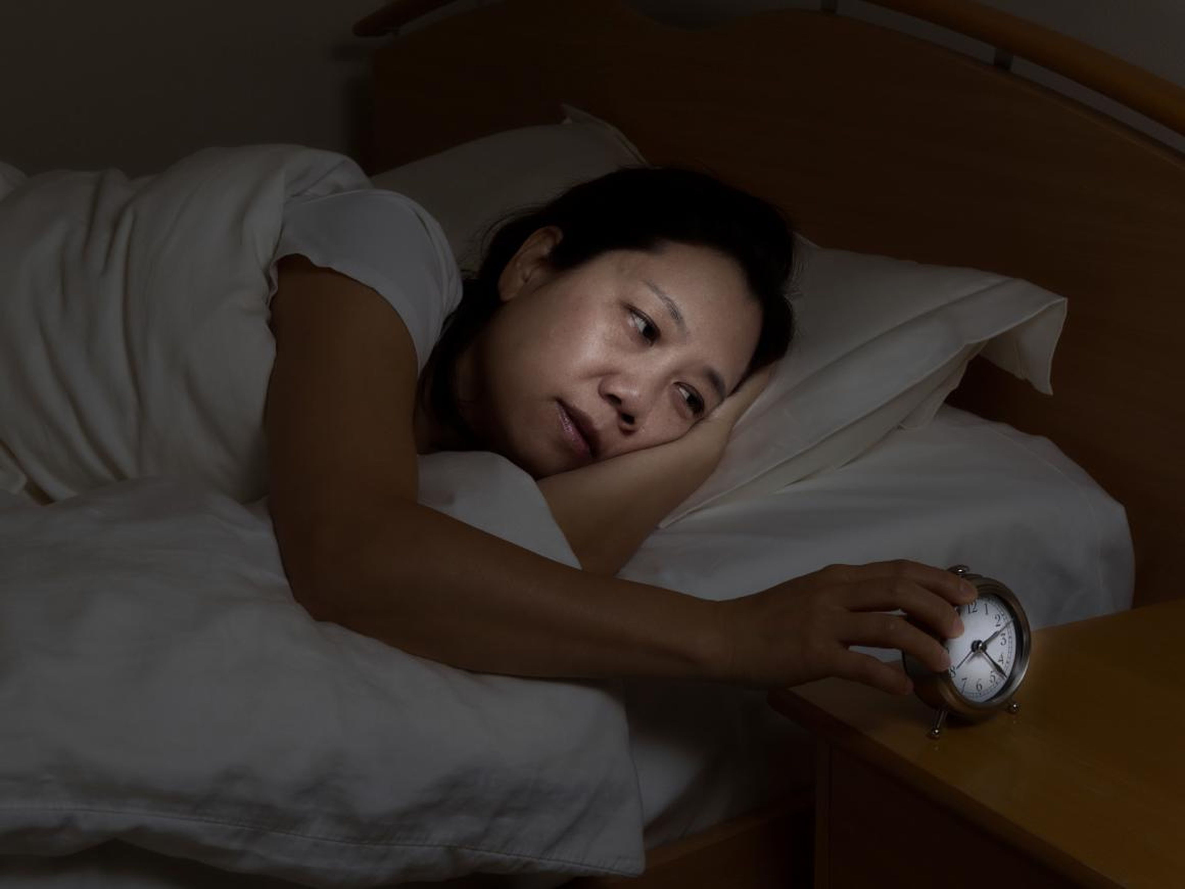 Mujer en la cama mirando el despertador