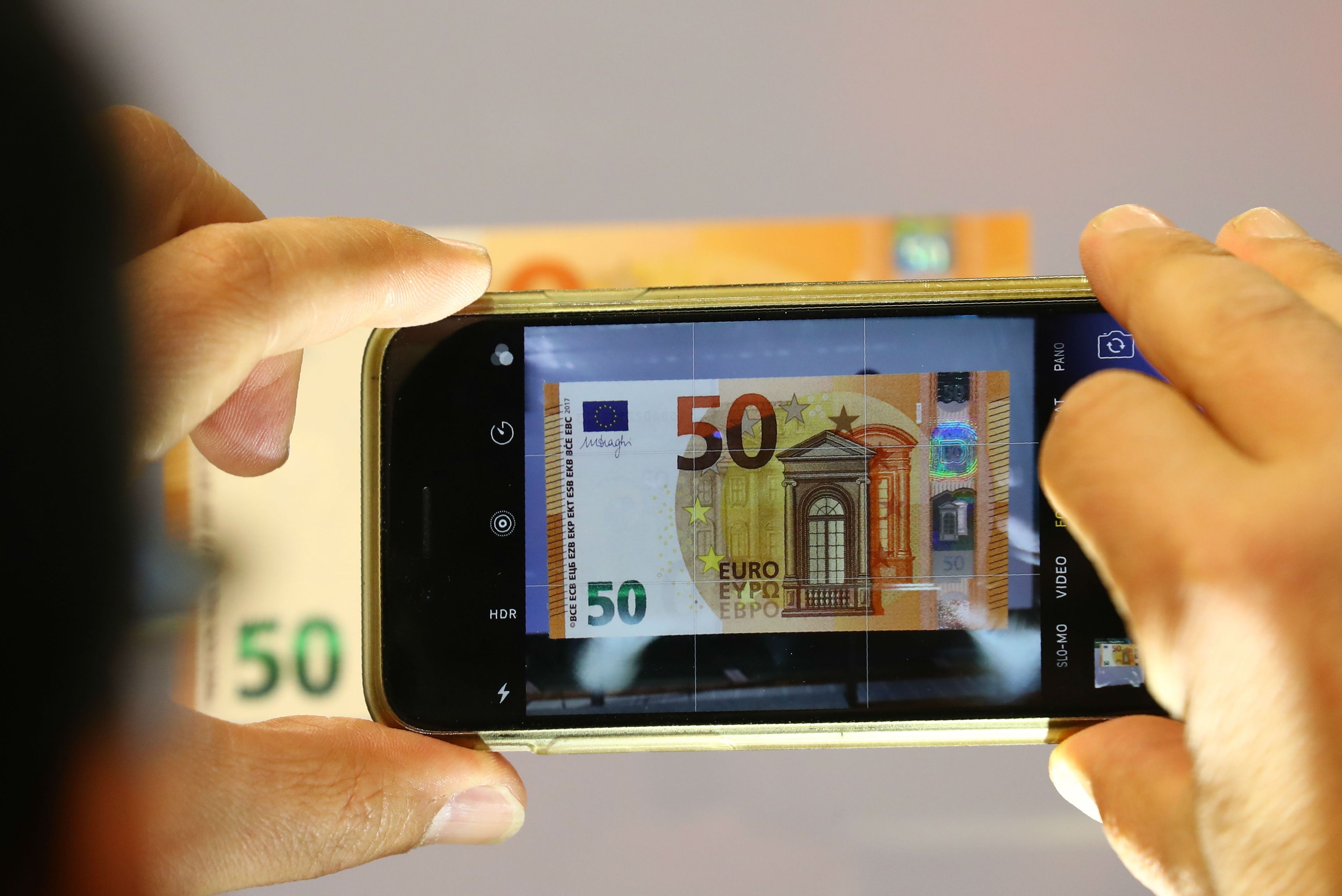 Una persona fotografía un billete de 50 euros.