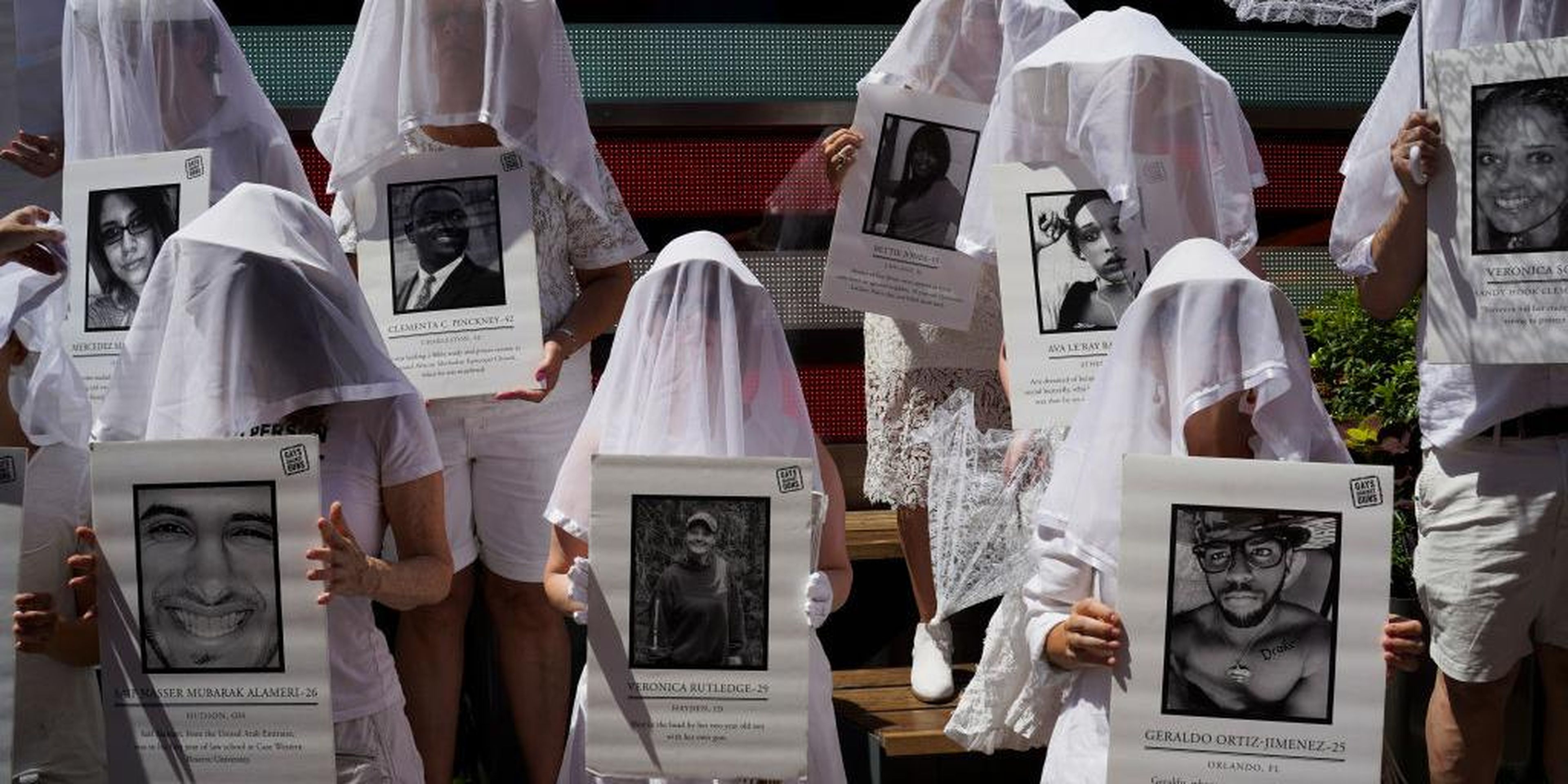 Manifestantes en contra de la violencia armada vestidos de blanco muestran fotos de las víctimas de la violencia armada en Times Square en respuesta a los recientes tiroteos masivos en El Paso, Texas y Denton, Ohio