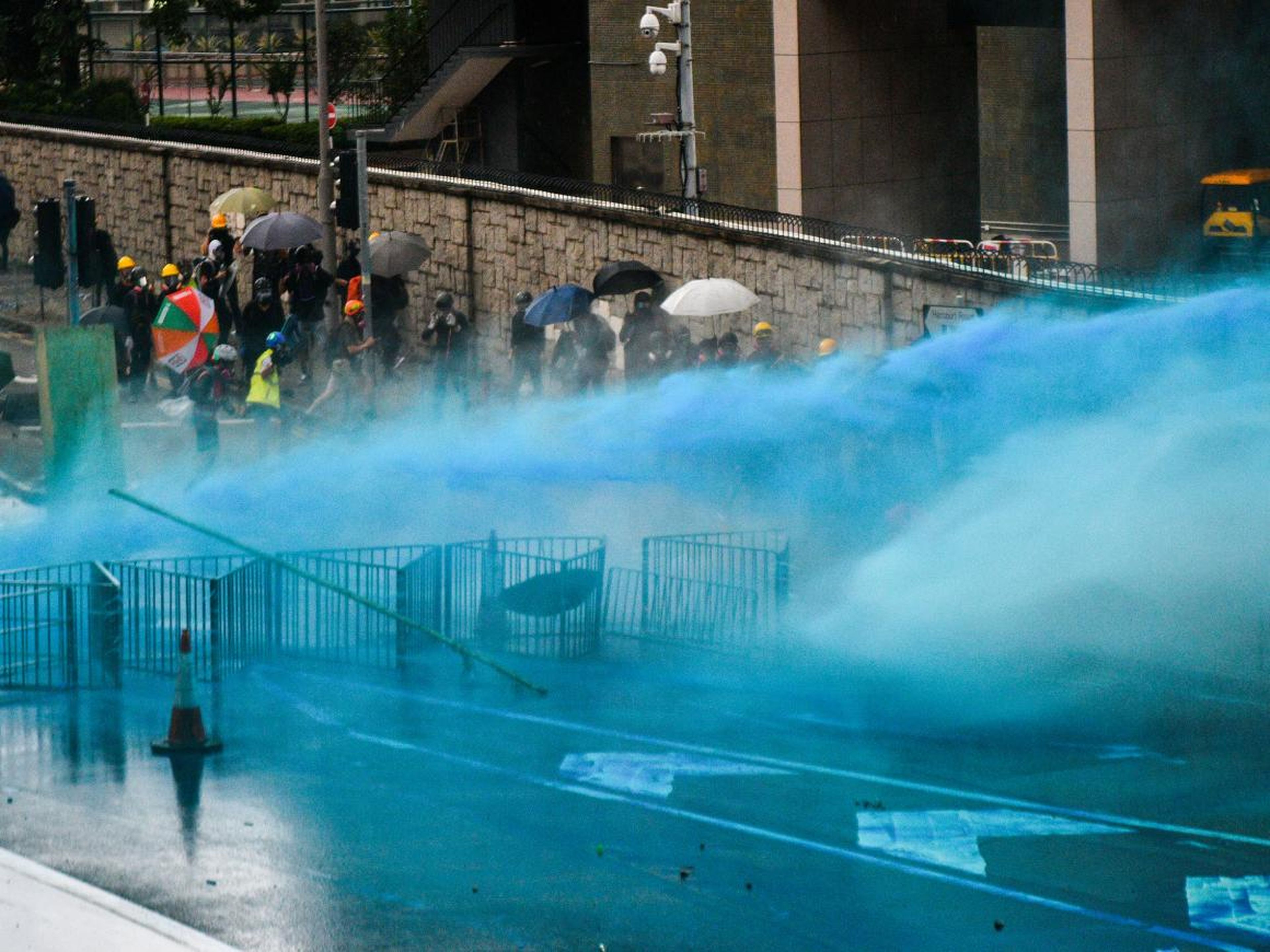 Water cannons coloured with blue dye spray protesters.