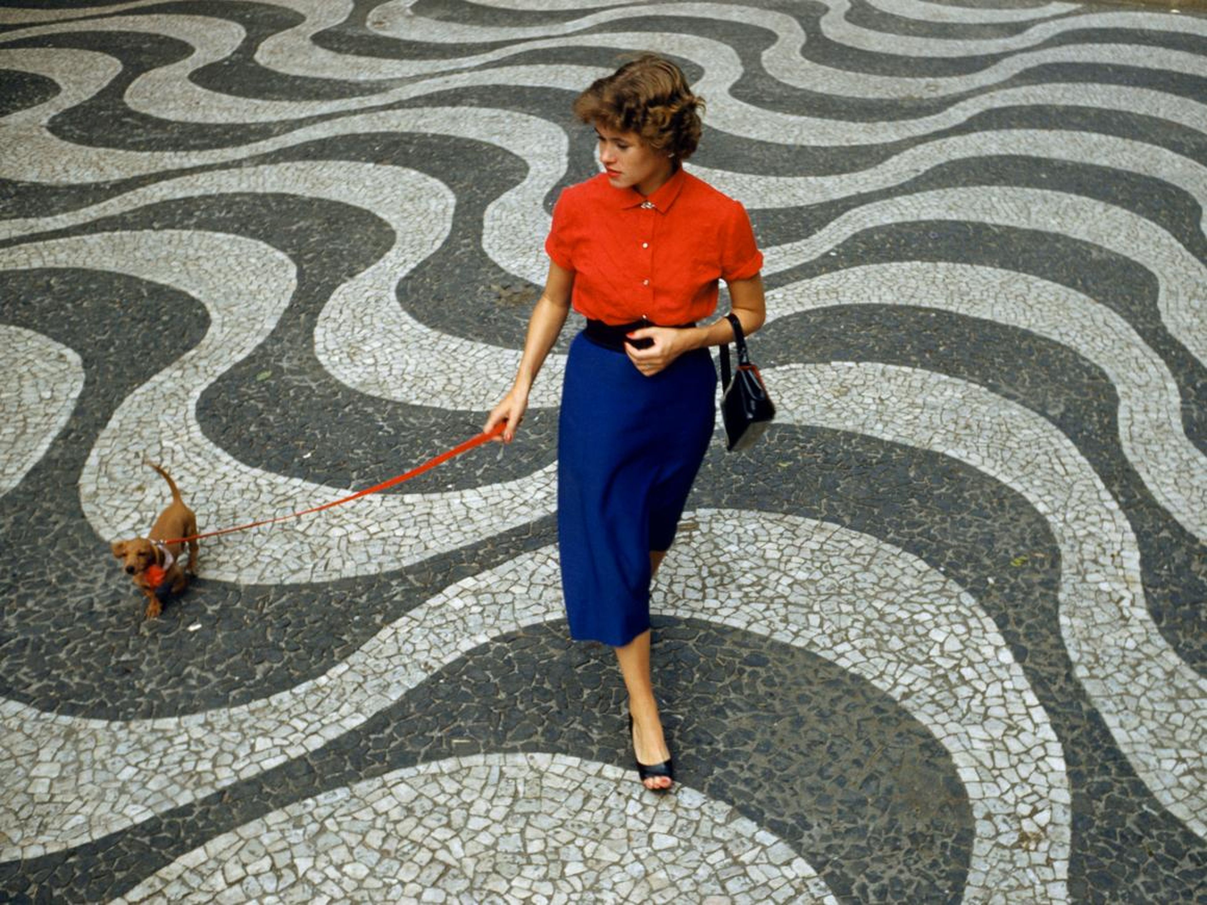 1950s: A woman walks her dachshund along the Copacabana Promenade in Rio de Janeiro, Brazil.