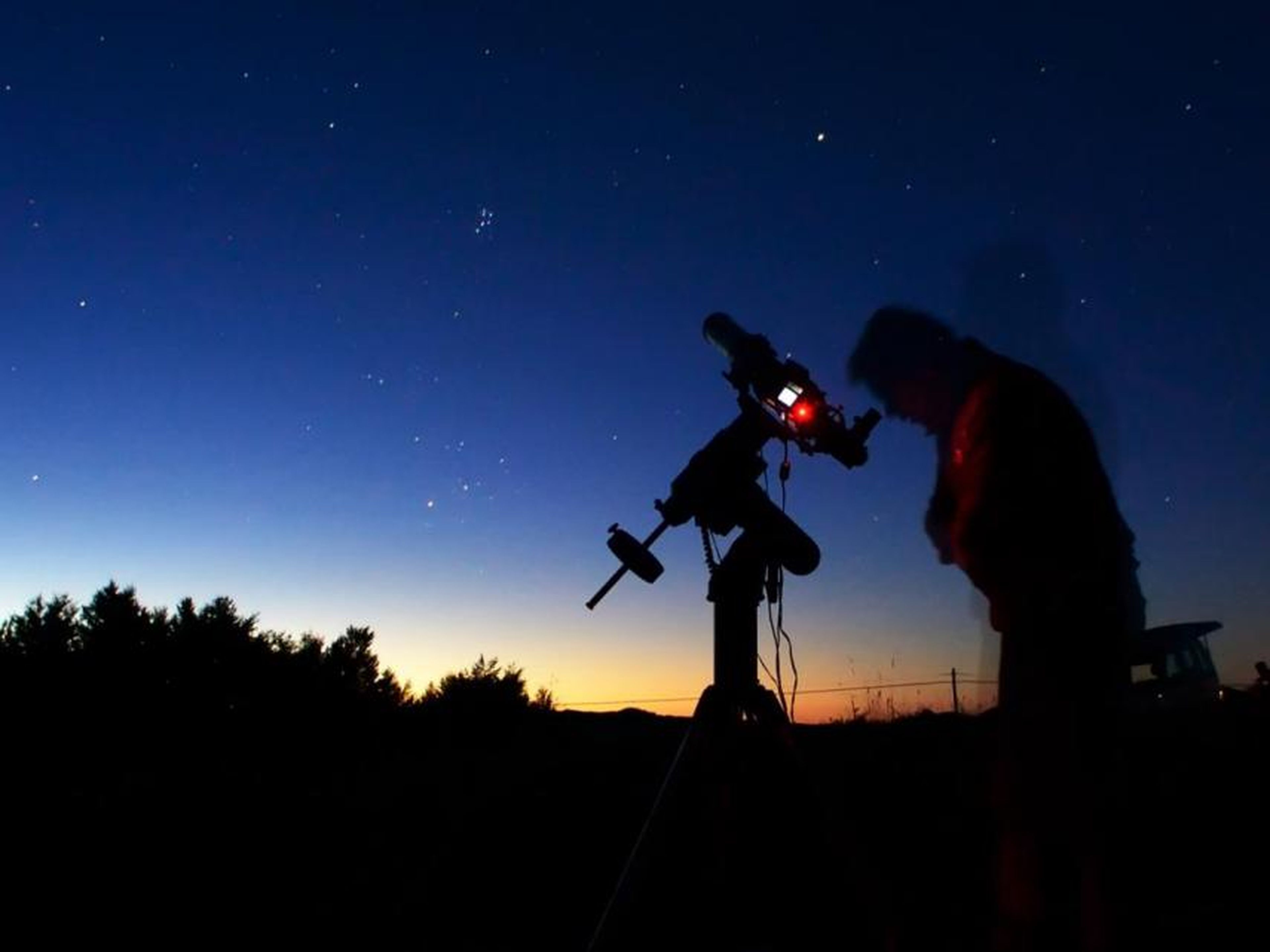 Un astrónomo aficionado mira a través de un pequeño telescopio.