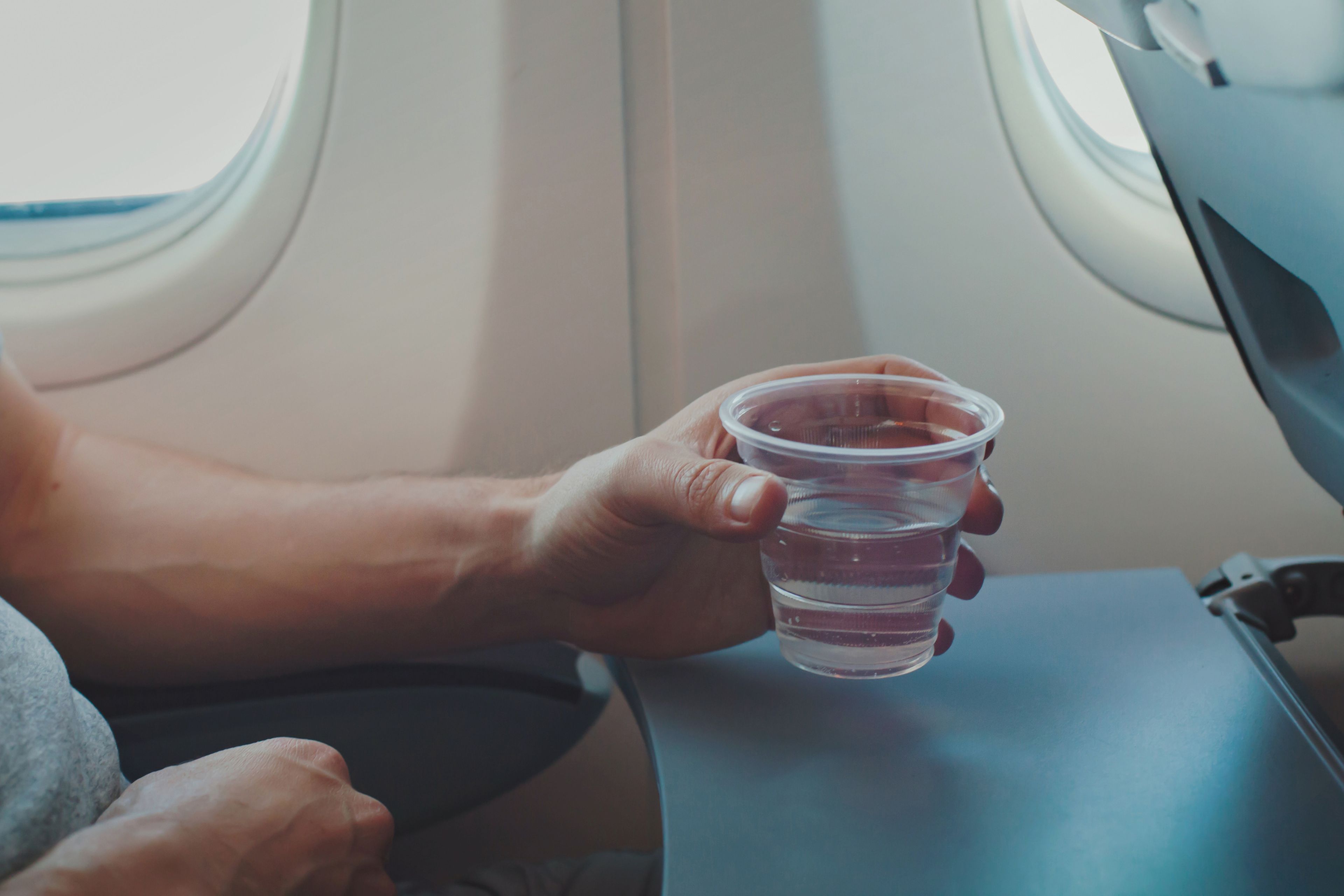 Un hombre bebiendo agua en el avión