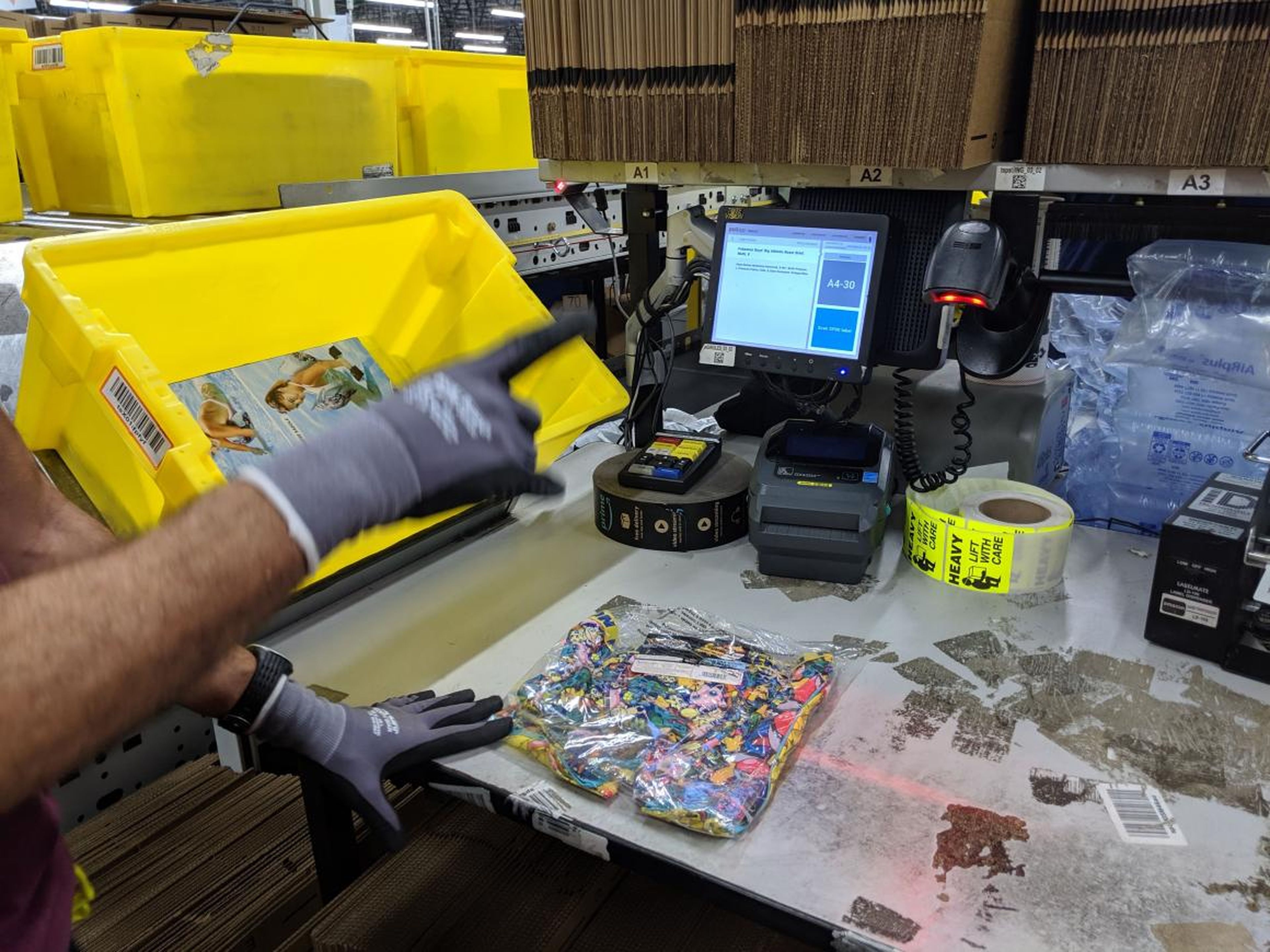 Items come into packing in the signature yellow totes, are scanned, and a bunch of information pops up telling the packer which type of box to use.