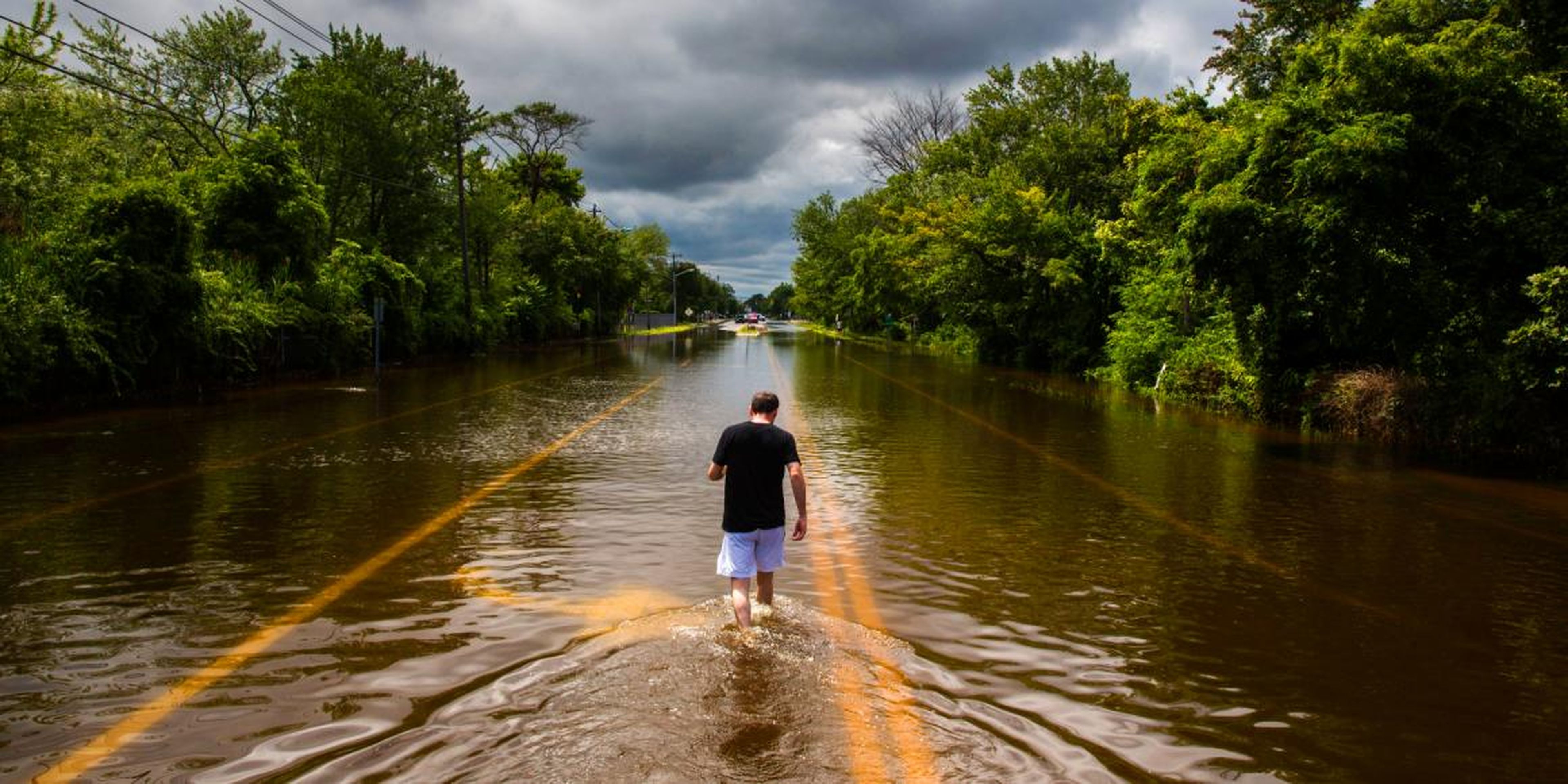 Un hombre camina por una carretera inundada en Islip, Nueva York en 2014.