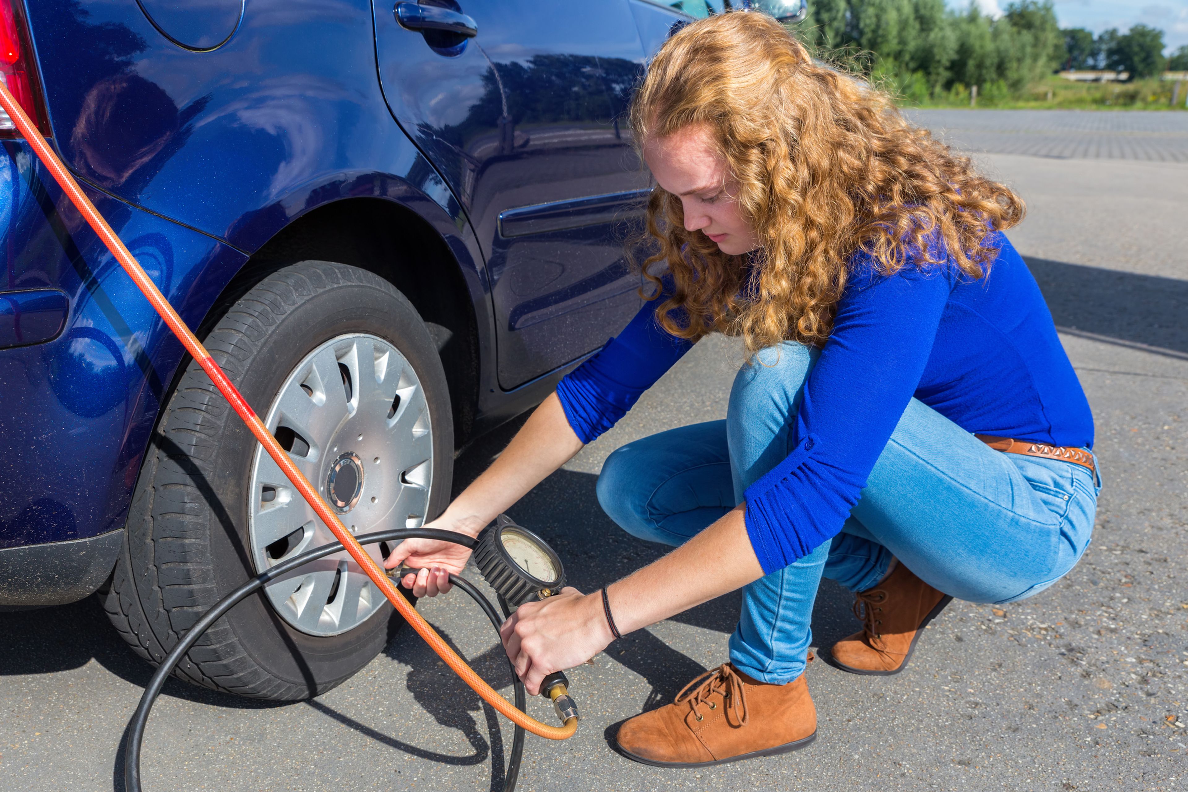 Una mujer infla un neumático del coche