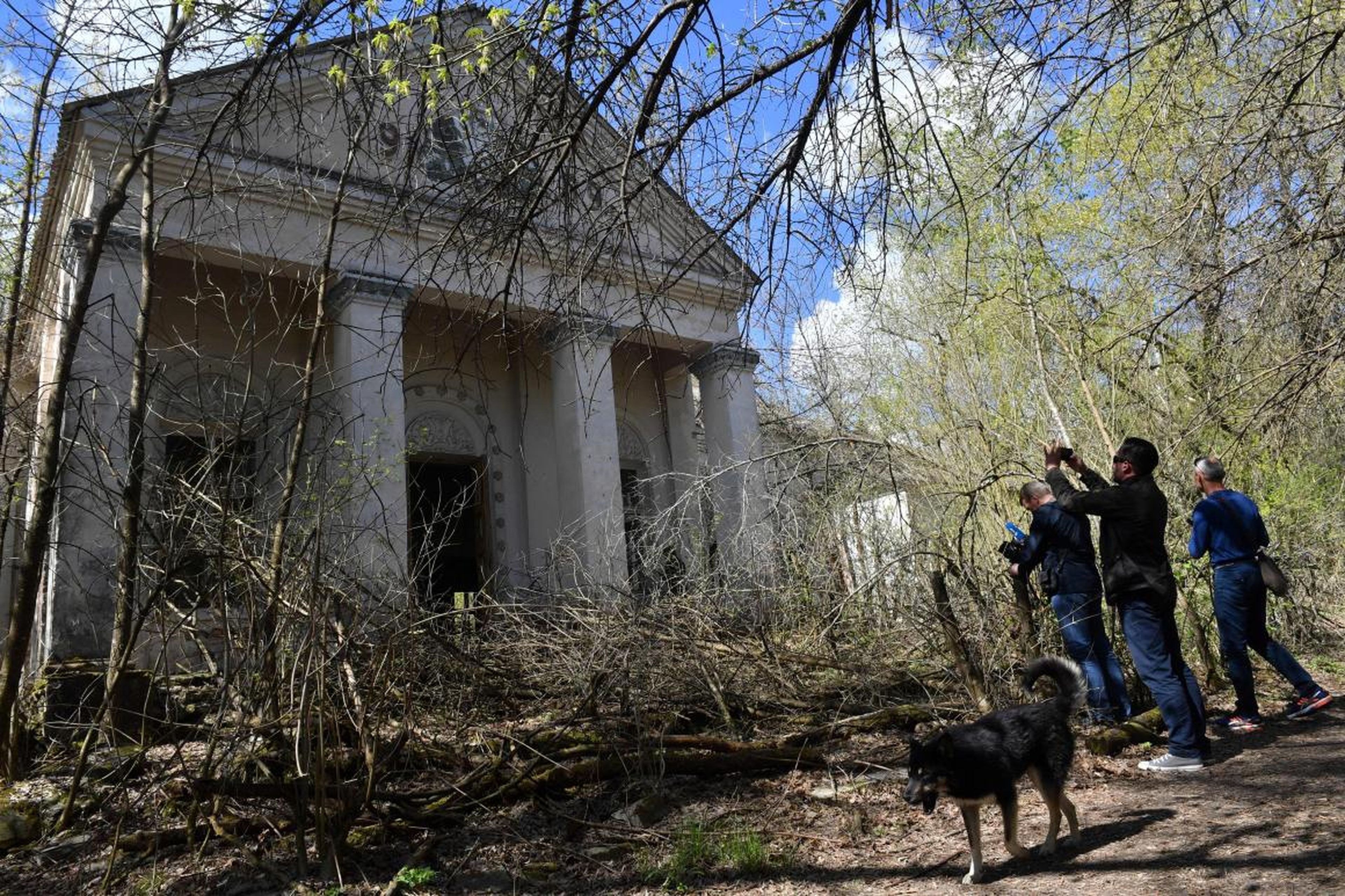 Los turistas hacen fotos de un edificio en el pueblo fantasma de Kopachi durante un recorrido por la Zona de Exclusión de Chernóbil el 23 de abril de 2018.