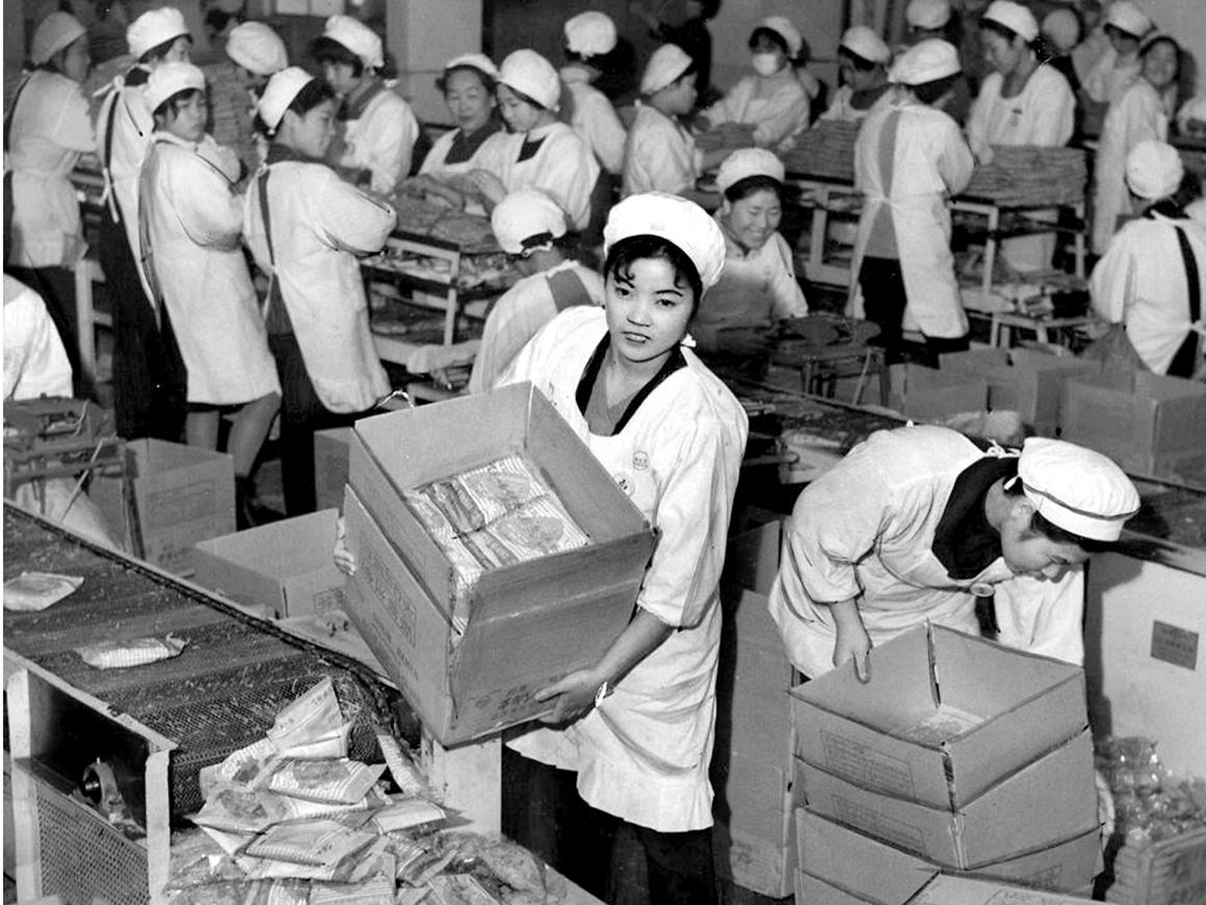Una chica de la fábrica sostiene una caja de'Chicken Ramen', el primer fideo instantáneo de la historia, en una fábrica de Nisshin Shokuhin en la década de 1960, Japón.