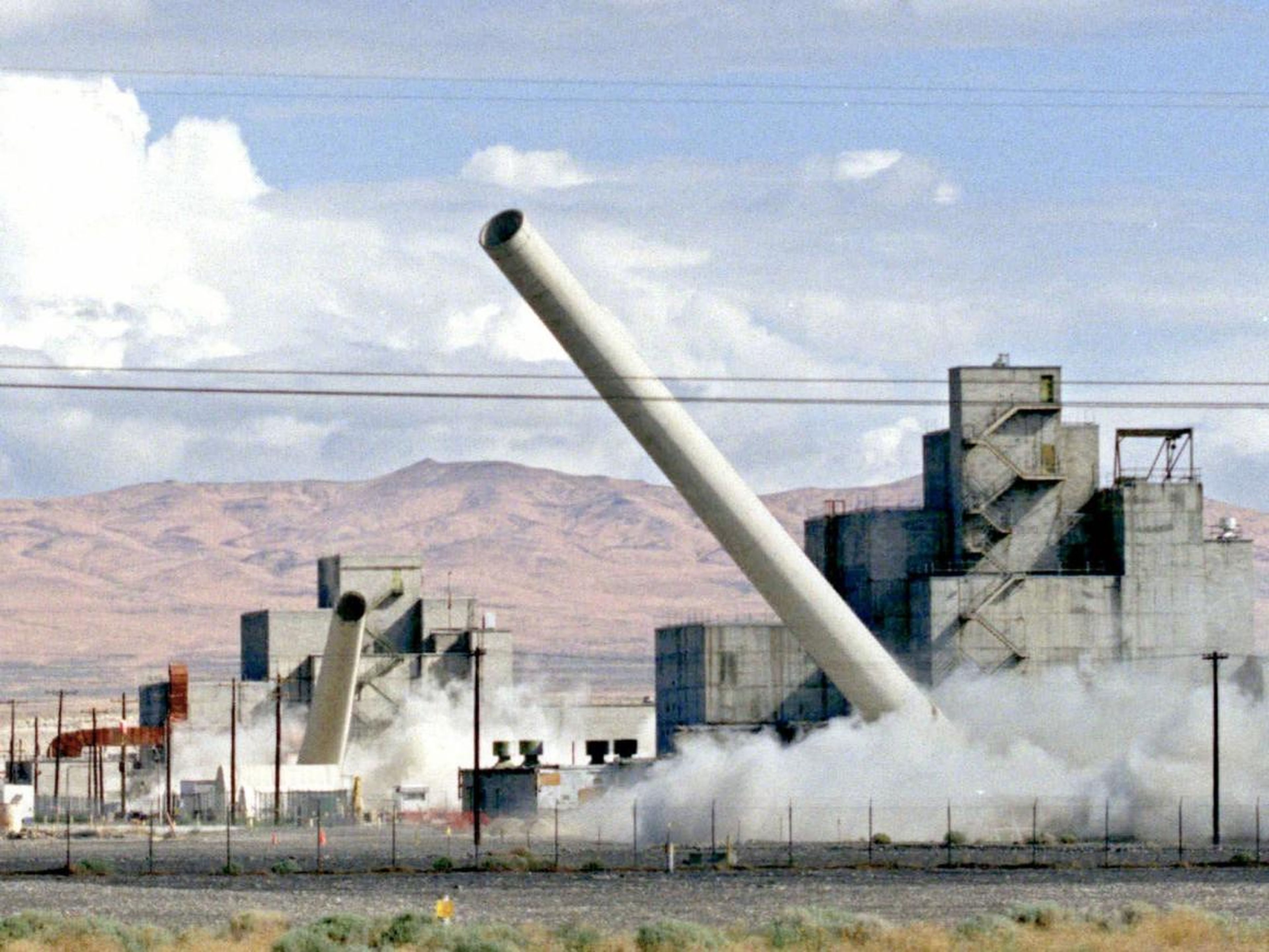 Las chimeneas de dos reactores de producción del Departamento de Energía caen en una demolición simultánea en la Reserva Nuclear de Hanford, cerca de Richland, Washington, el sábado 14 de agosto de 1999.