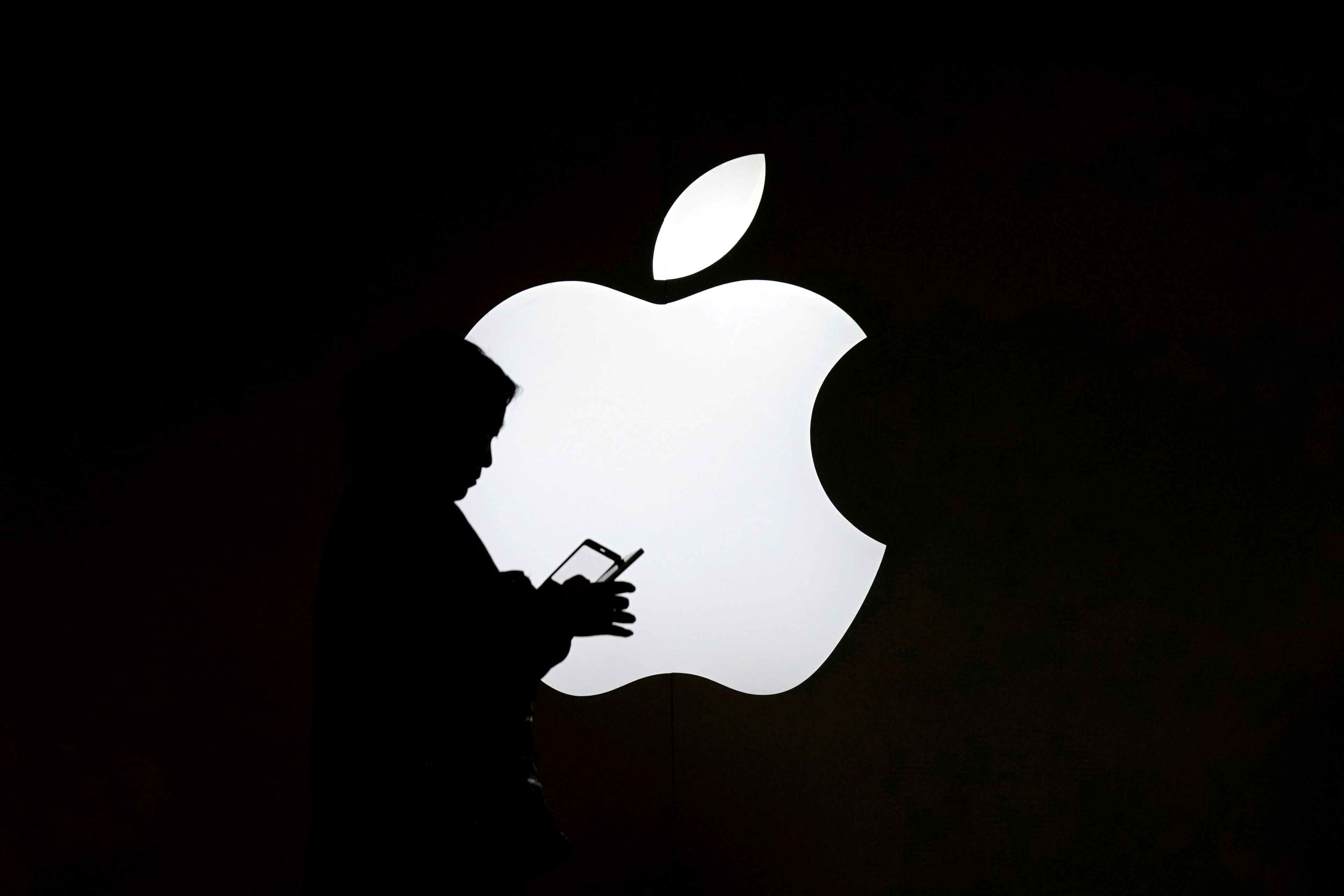 Una persona pasa por delante del logotipo de Apple