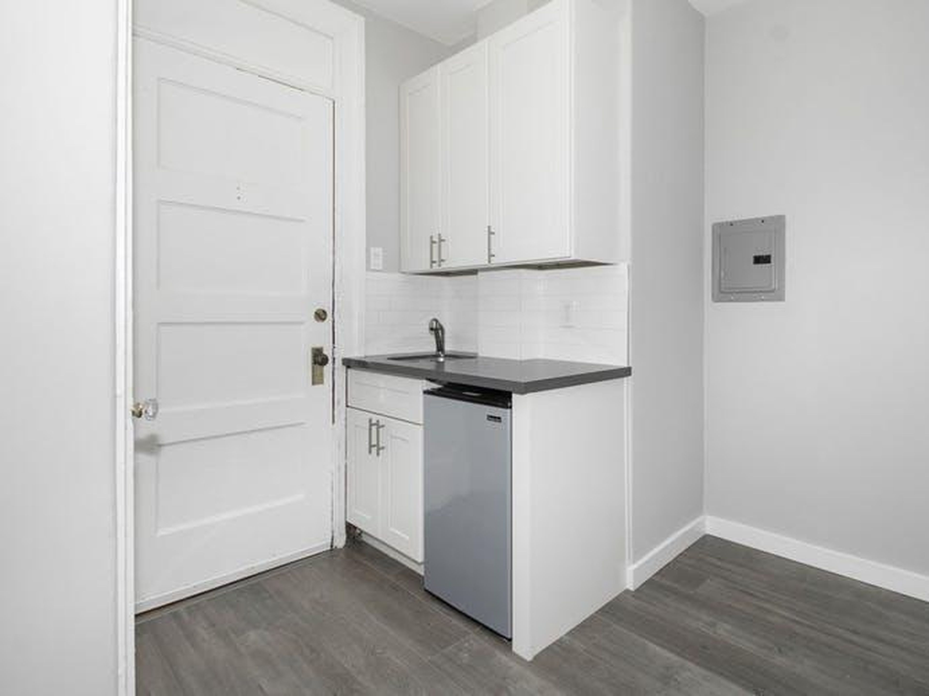 The sink, which can be seen below, is right next to the studio's front door — and the kitchen seems to consist of that, a mini fridge, and not much else.