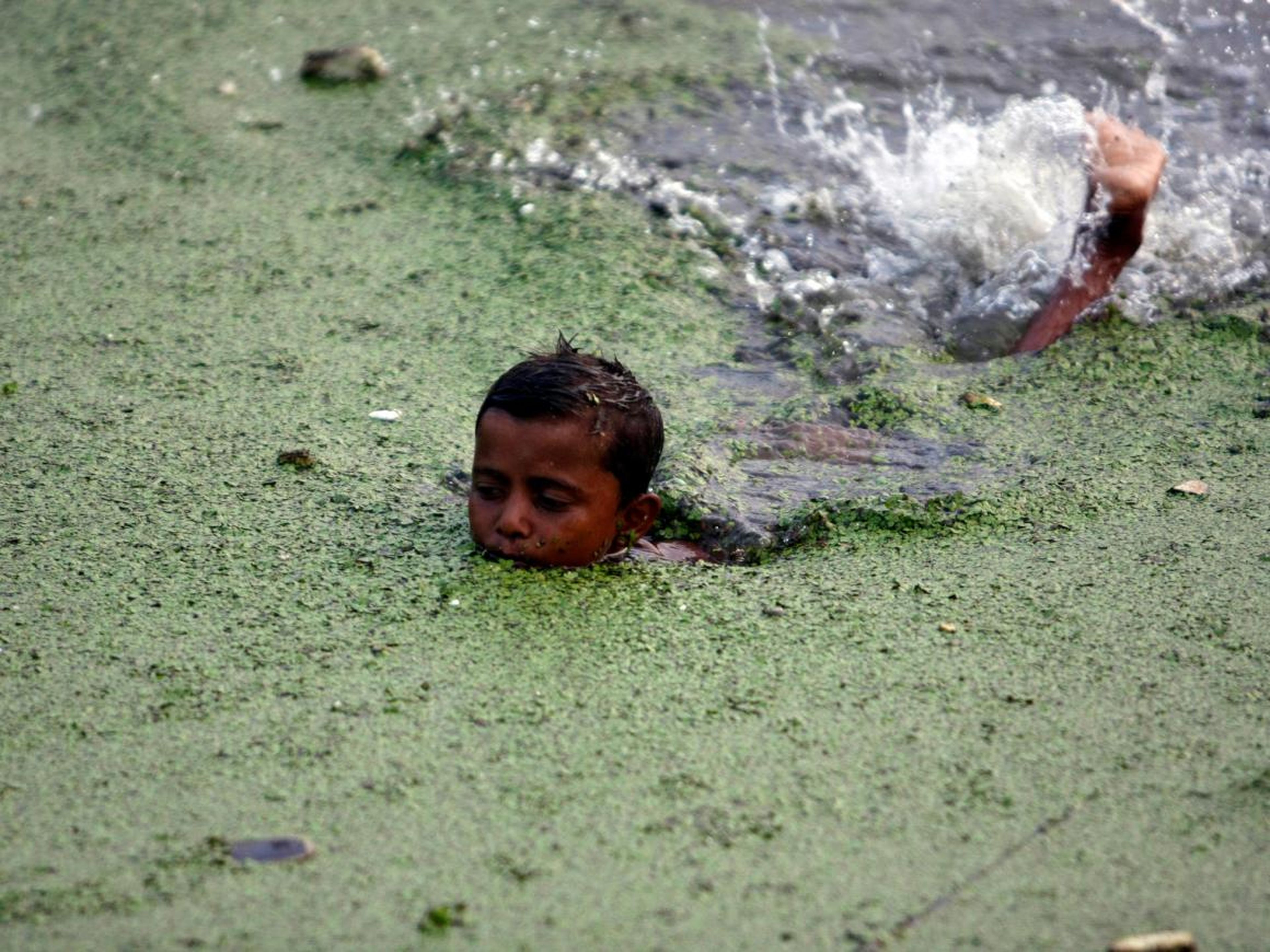 Un niño nada en agua contaminada en el río Buriganga en Dhaka (Bangladesh).