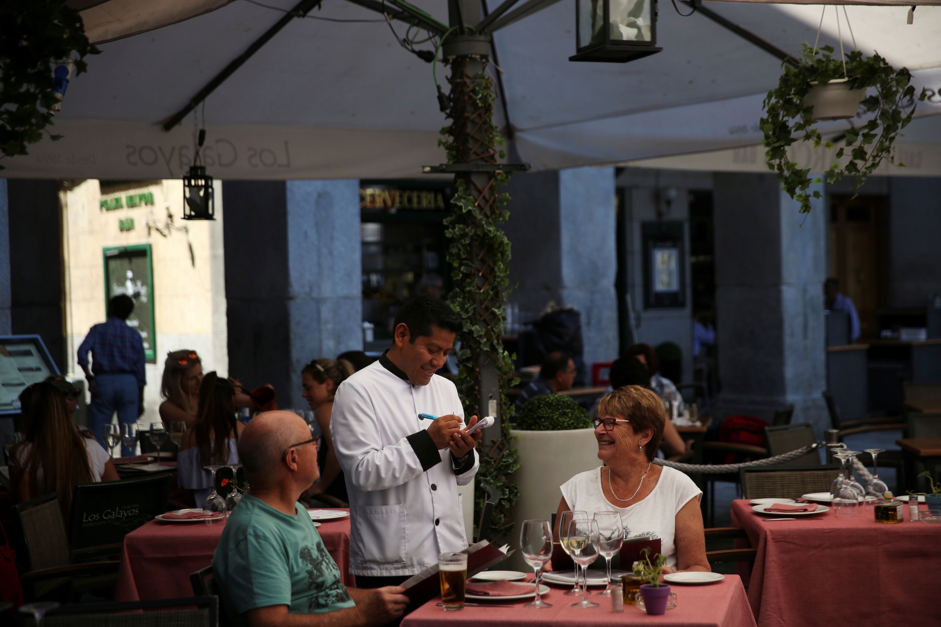 Un camarero atiende a una pareja de turistas en una terraza de Málaga