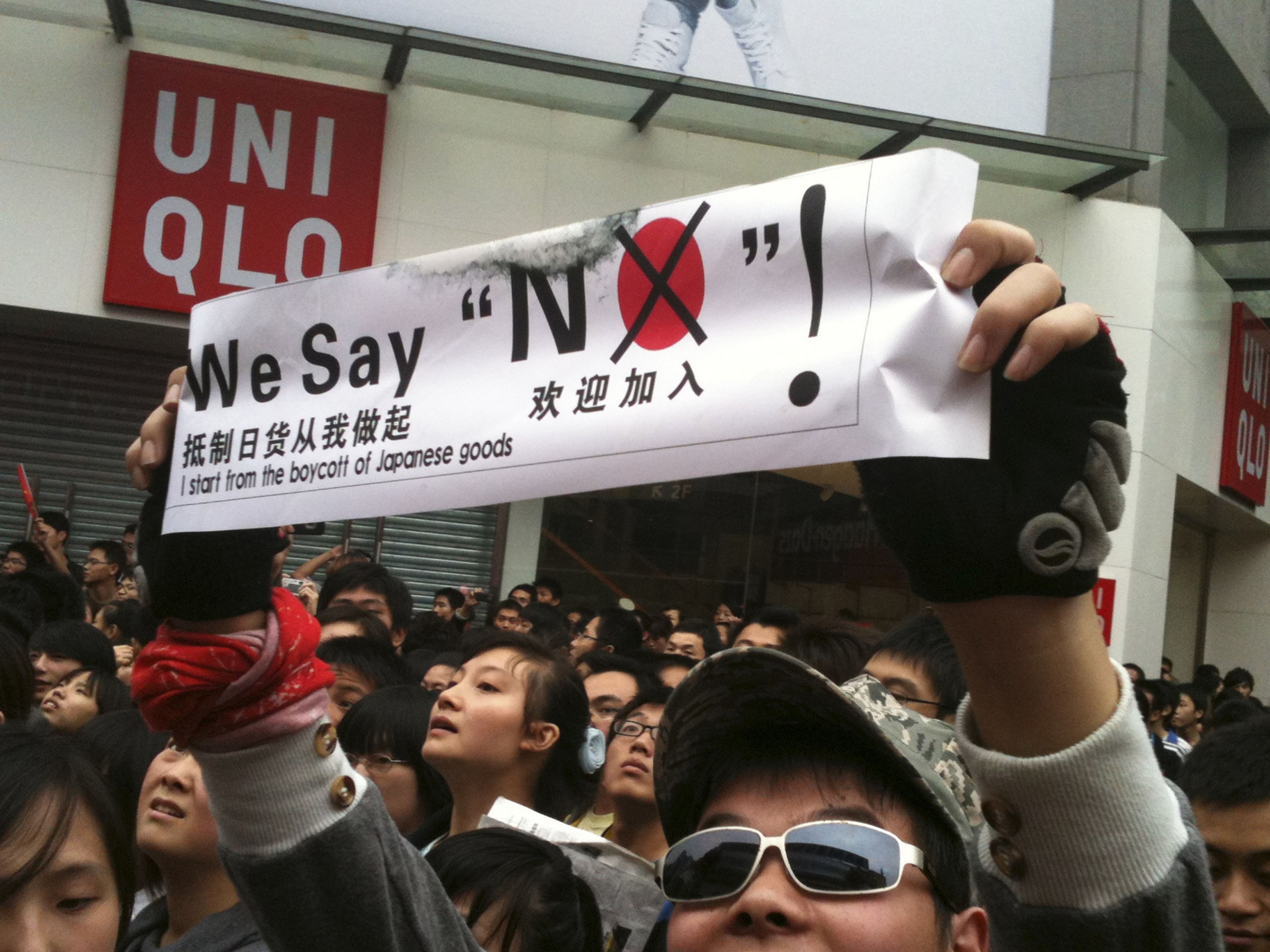 En China, un manifestante con una pancarta de "boicot a los productos japoneses" fuera de una tienda de Uniqlo de Japón durante las protestas por las islas Diaoyu y Senkaku contra Japón en 2010.