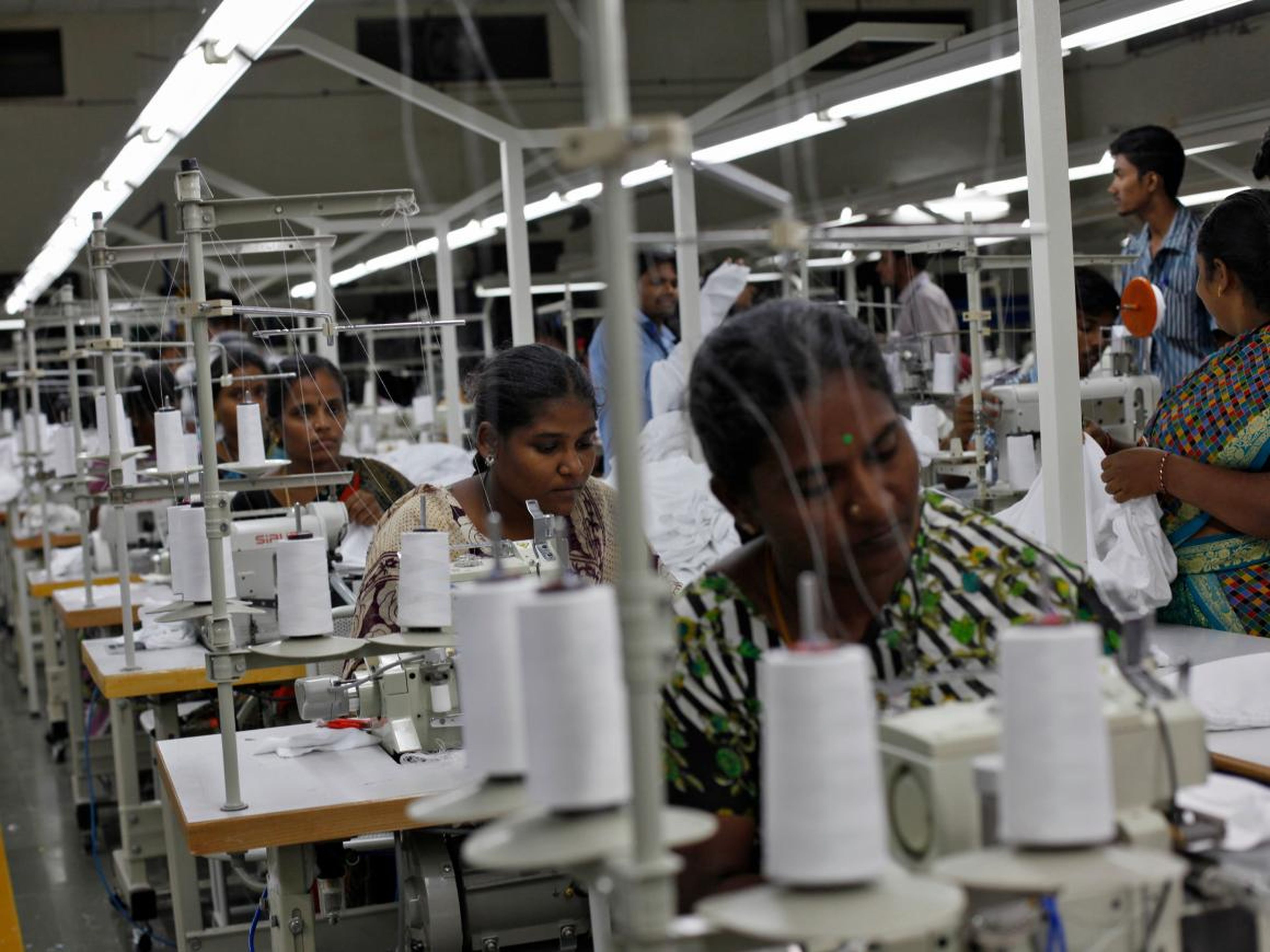 Empleados cosen ropa en una fábrica de ropa en la India.