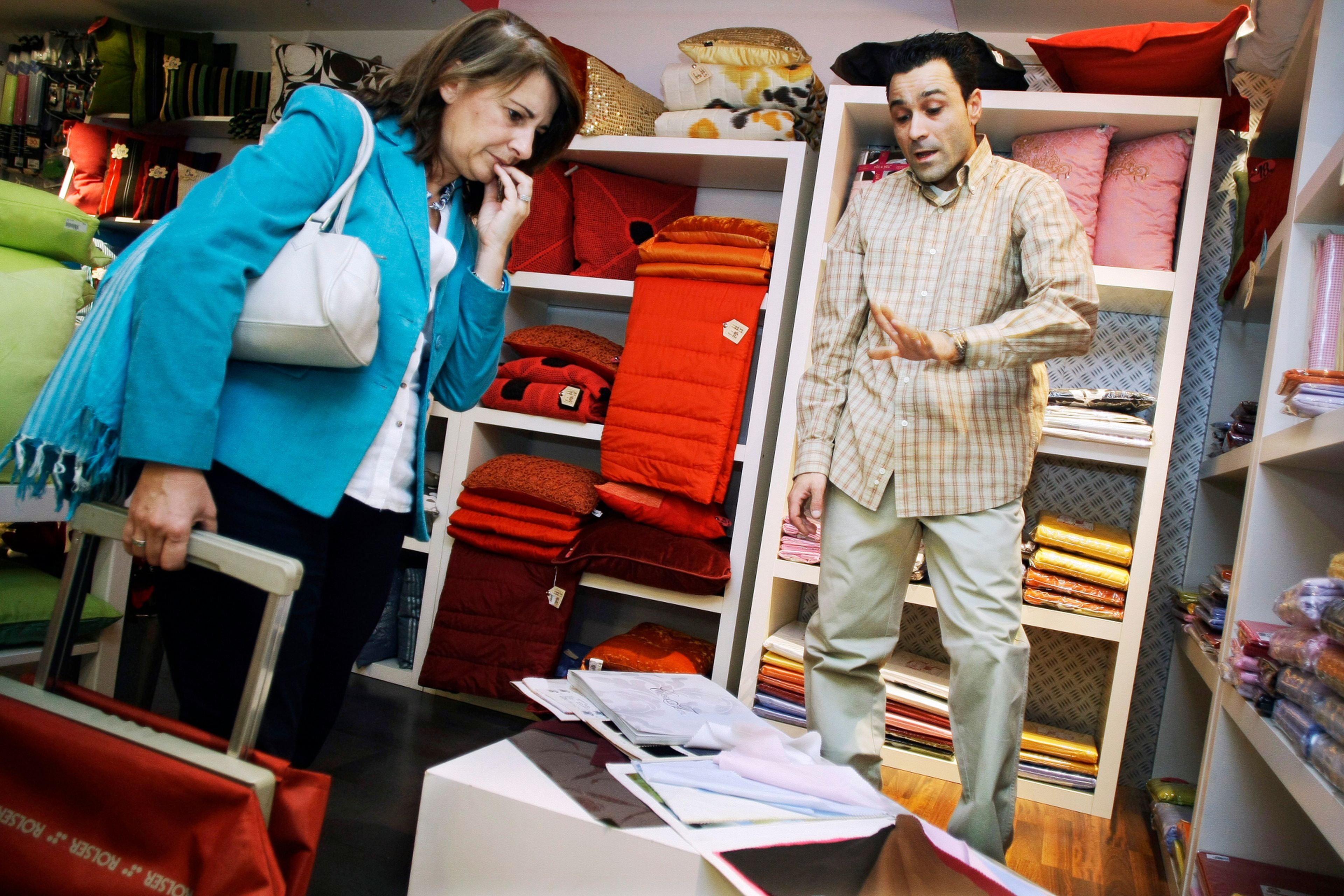 Un comerciante textil atiende a una clienta en su tienda