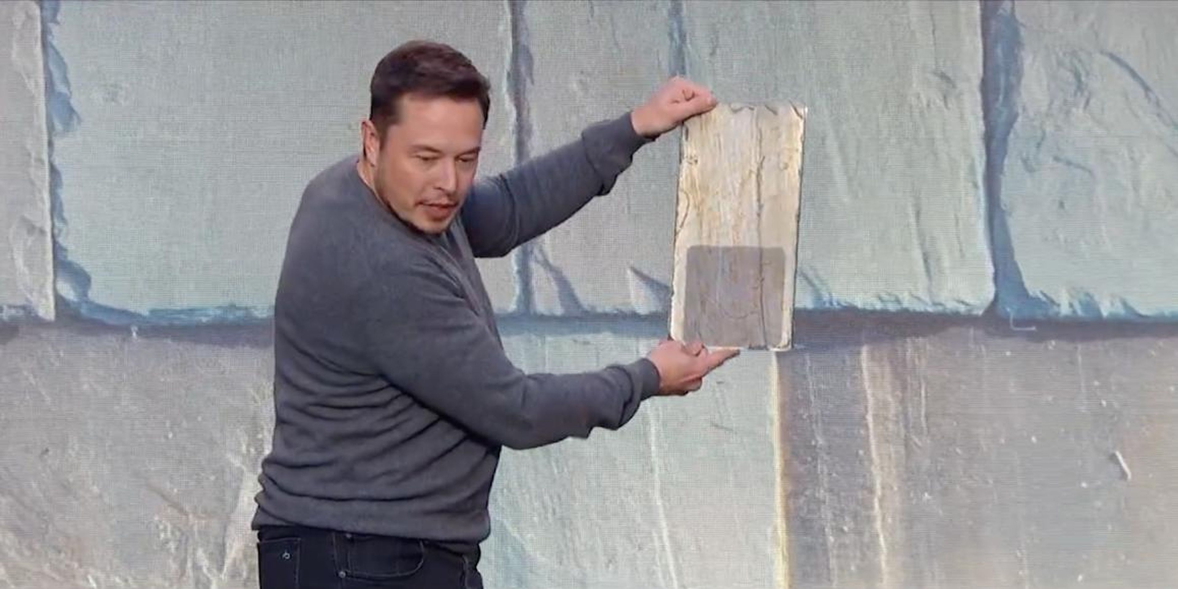 Elon Musk showing off an earlier version of Tesla's solar-roof panel.