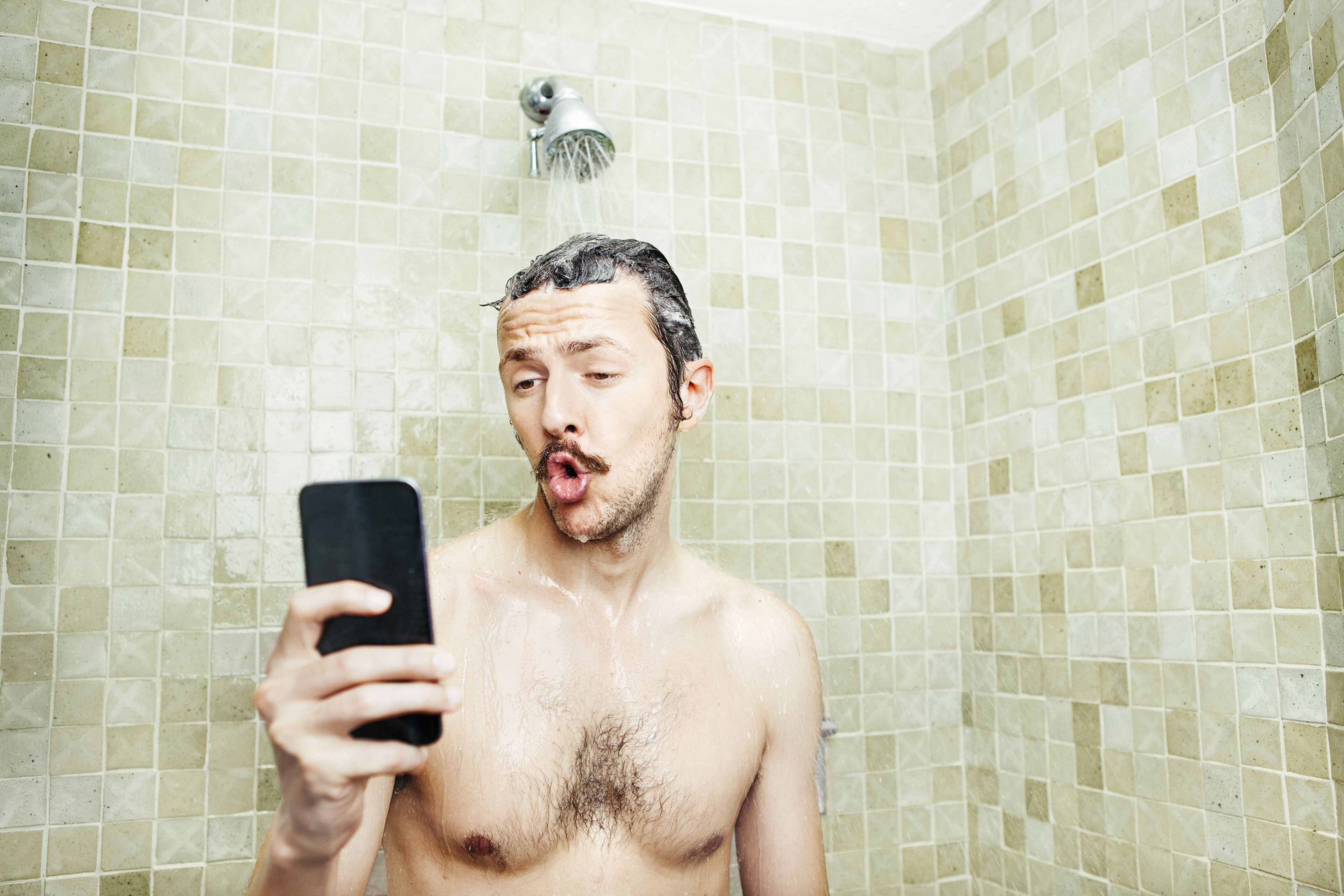 Un hombre usa el móvil en la ducha