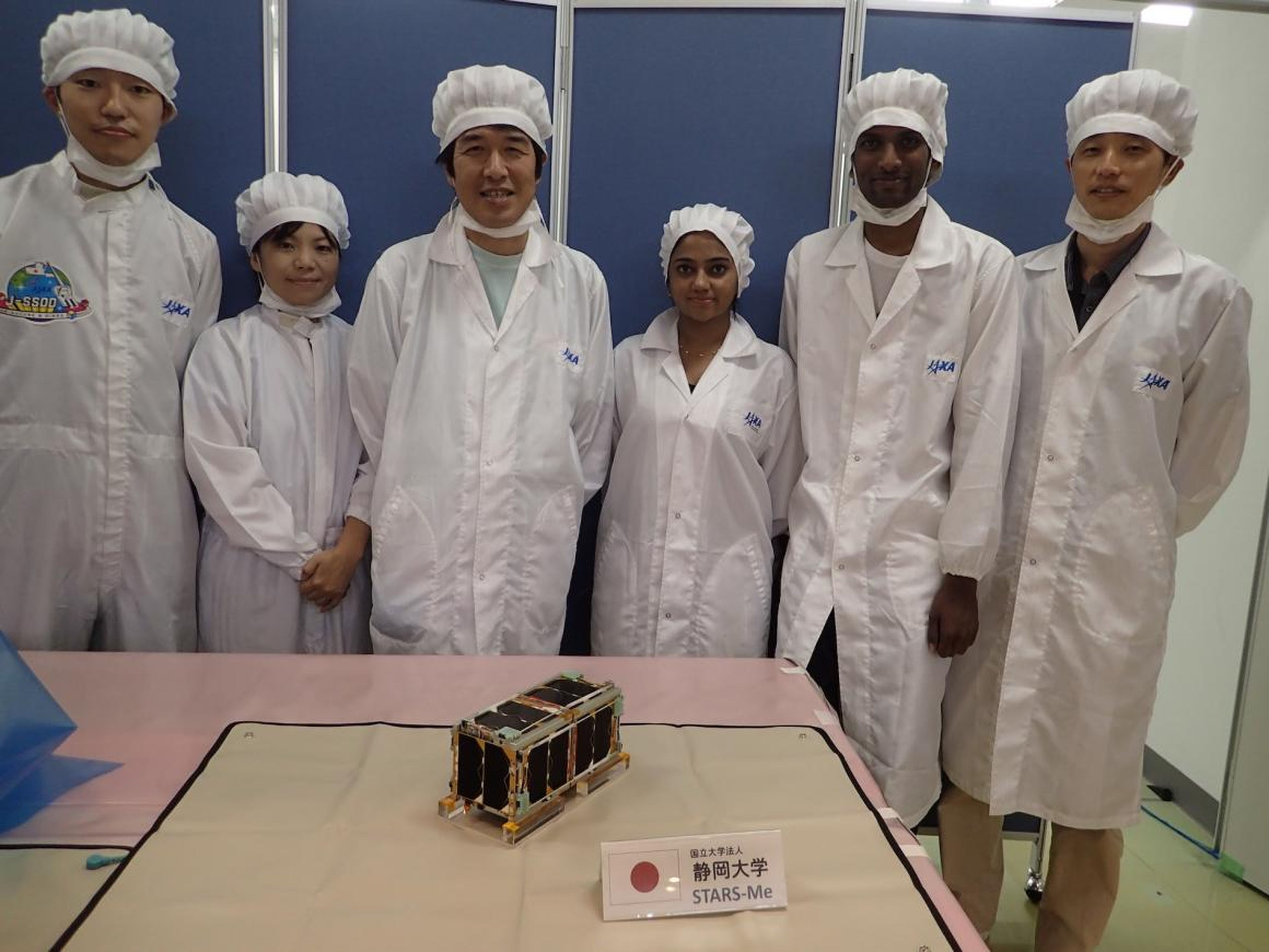 Los equipos de desarrollo de CubeSat y los funcionarios de JAXA posan con una demostración a pequeña escala del ascensor orbital STARS-Me, en agosto de 2018.