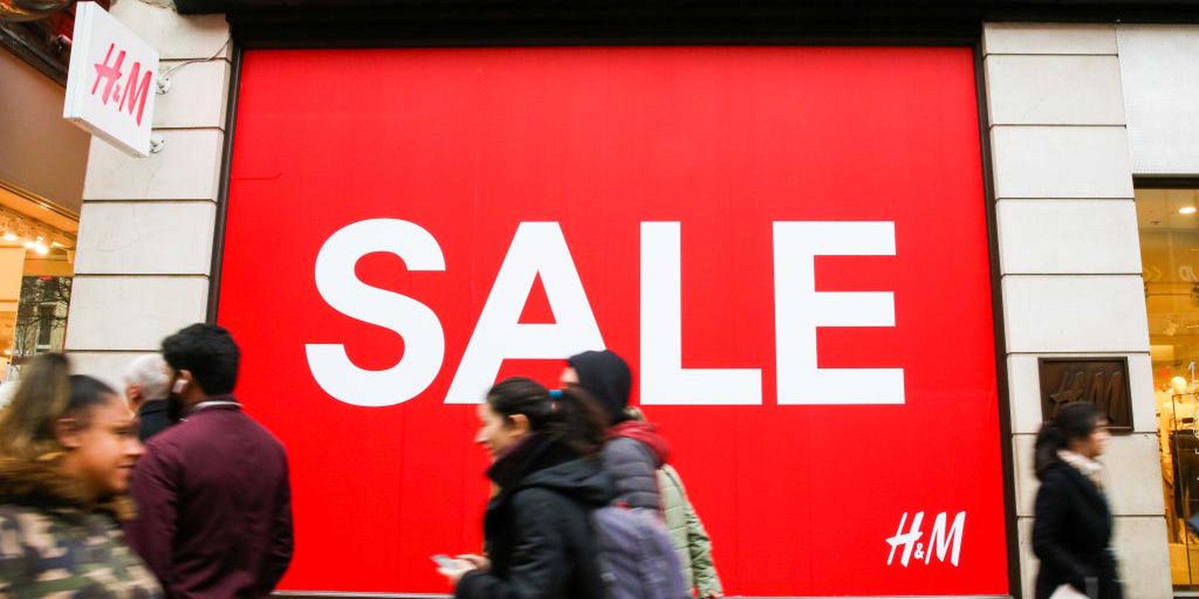 Shoppers are seen walking past H&M window display with a large SALE sign. Last minute Christmas shoppers take advantage of pre-Christmas bargains at Oxford Street in London. Fewer shoppers have been reported shopping in Britain's