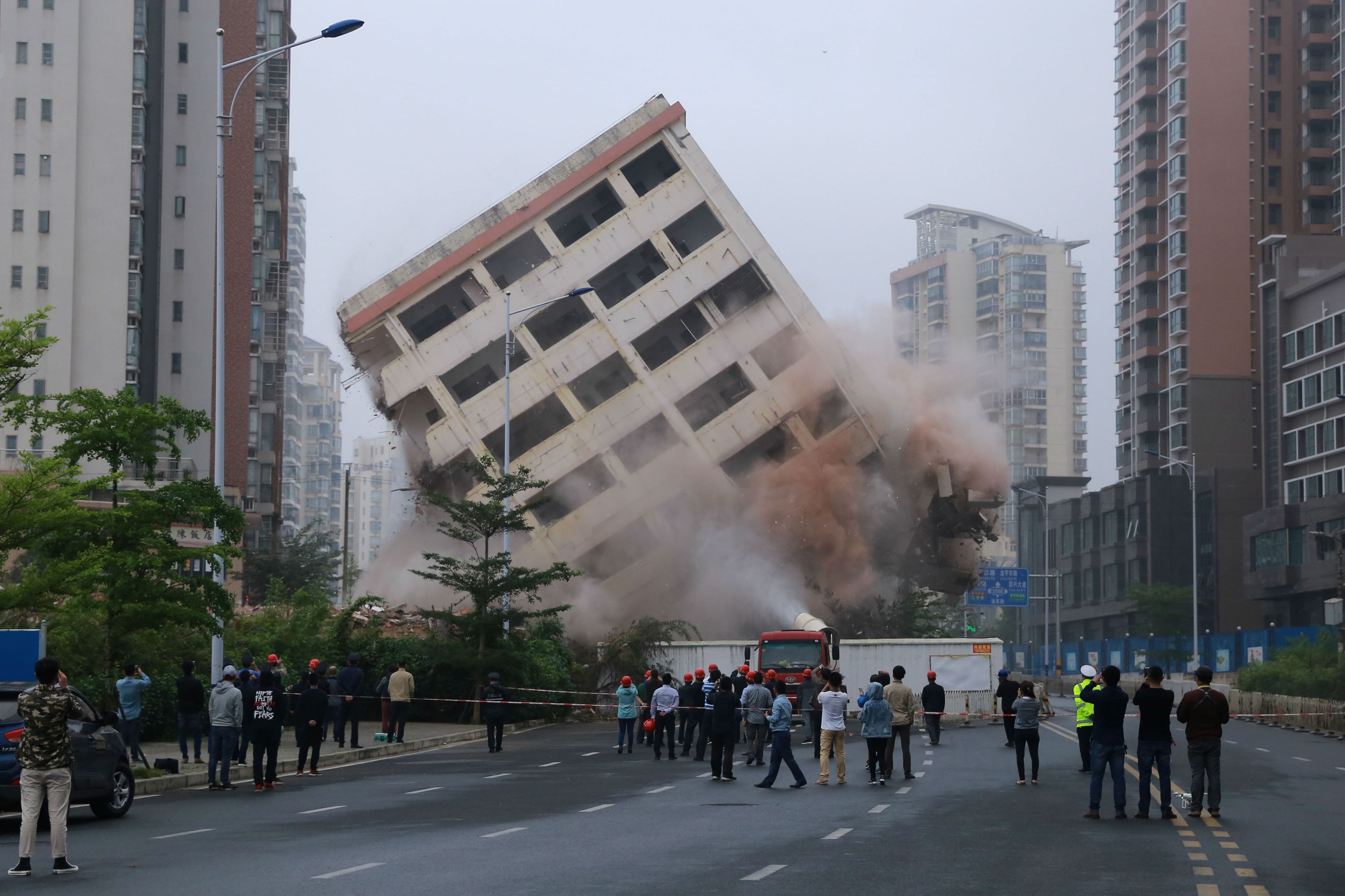 Varias personas observan la voladura controlada de un edificio en China.