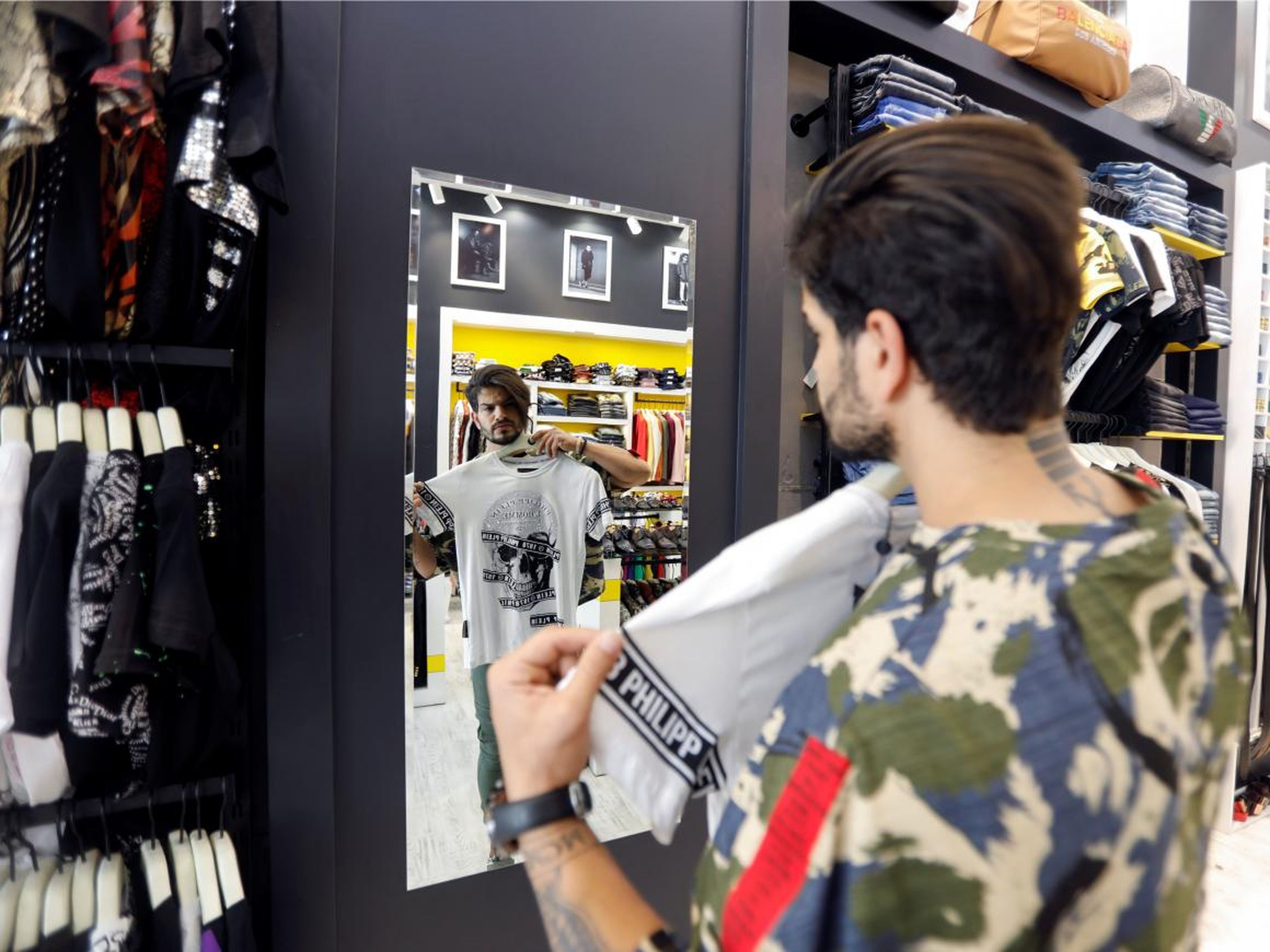Un hombre iraquí se mira en el espejo mientras compra.