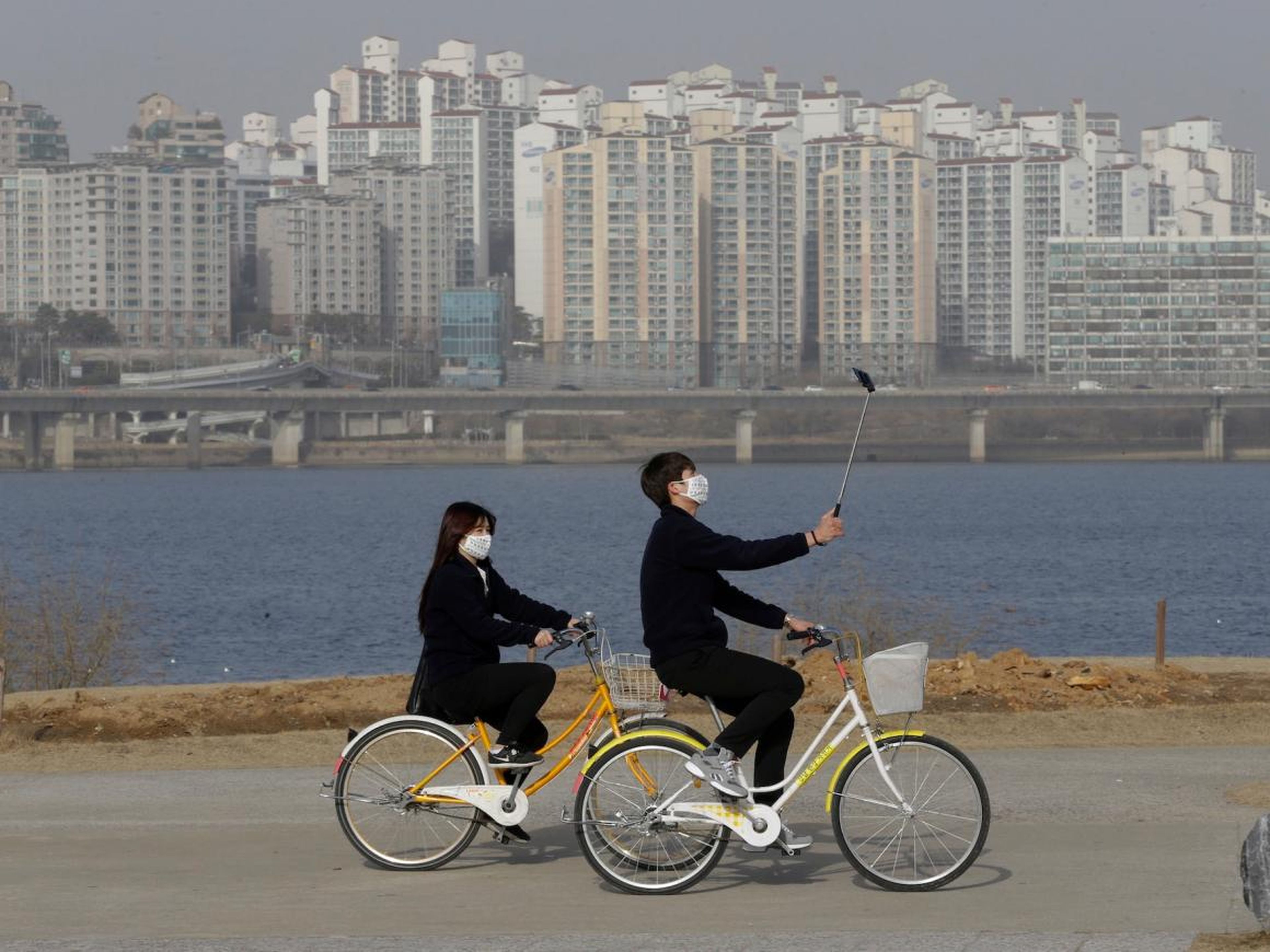 A pair of cyclists, with one holding a selfie stick, in Seoul, South Korea.