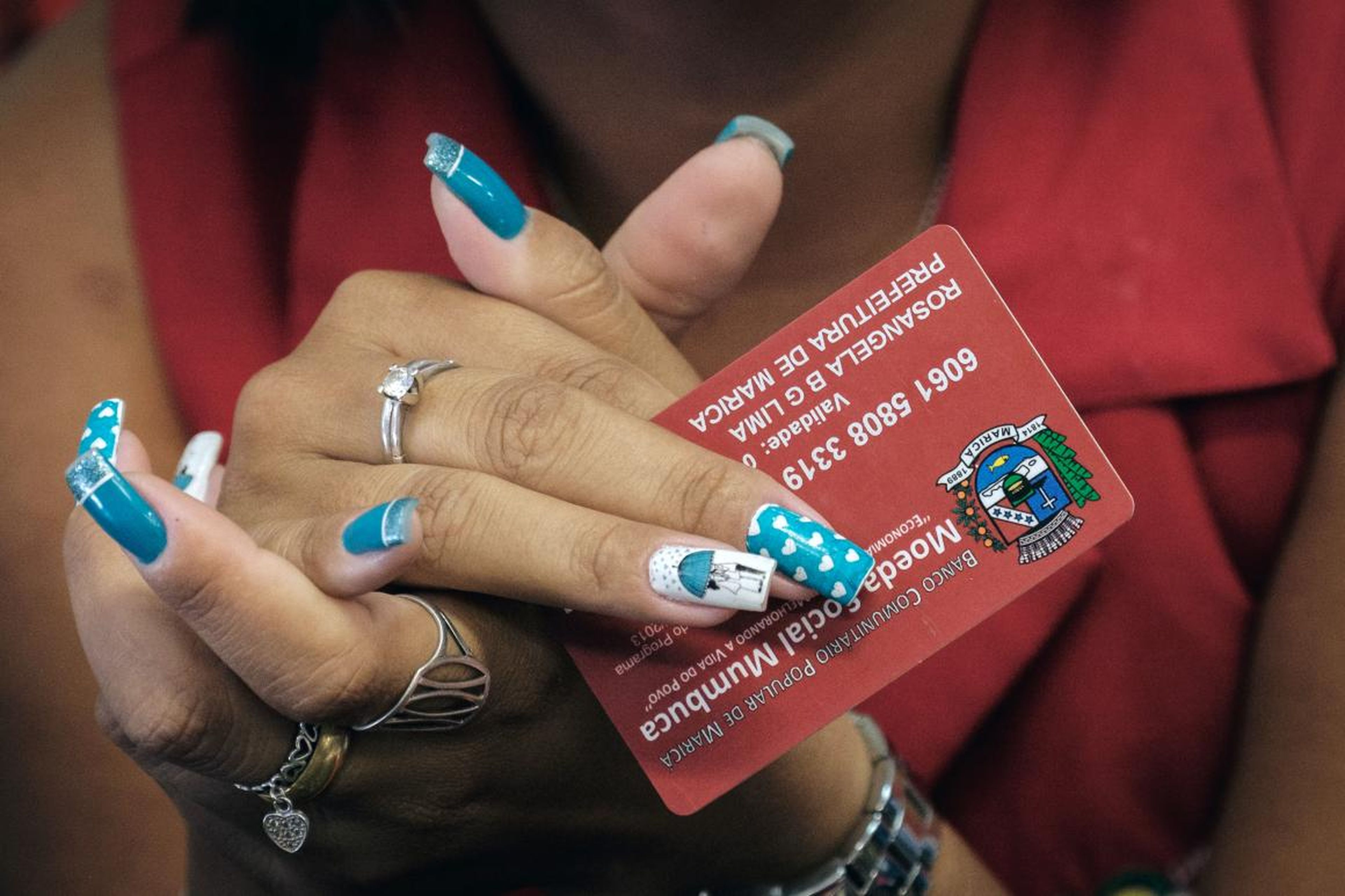 A cashier holds a "mumbuca" card at a pharmacy in Marica, Brazil.