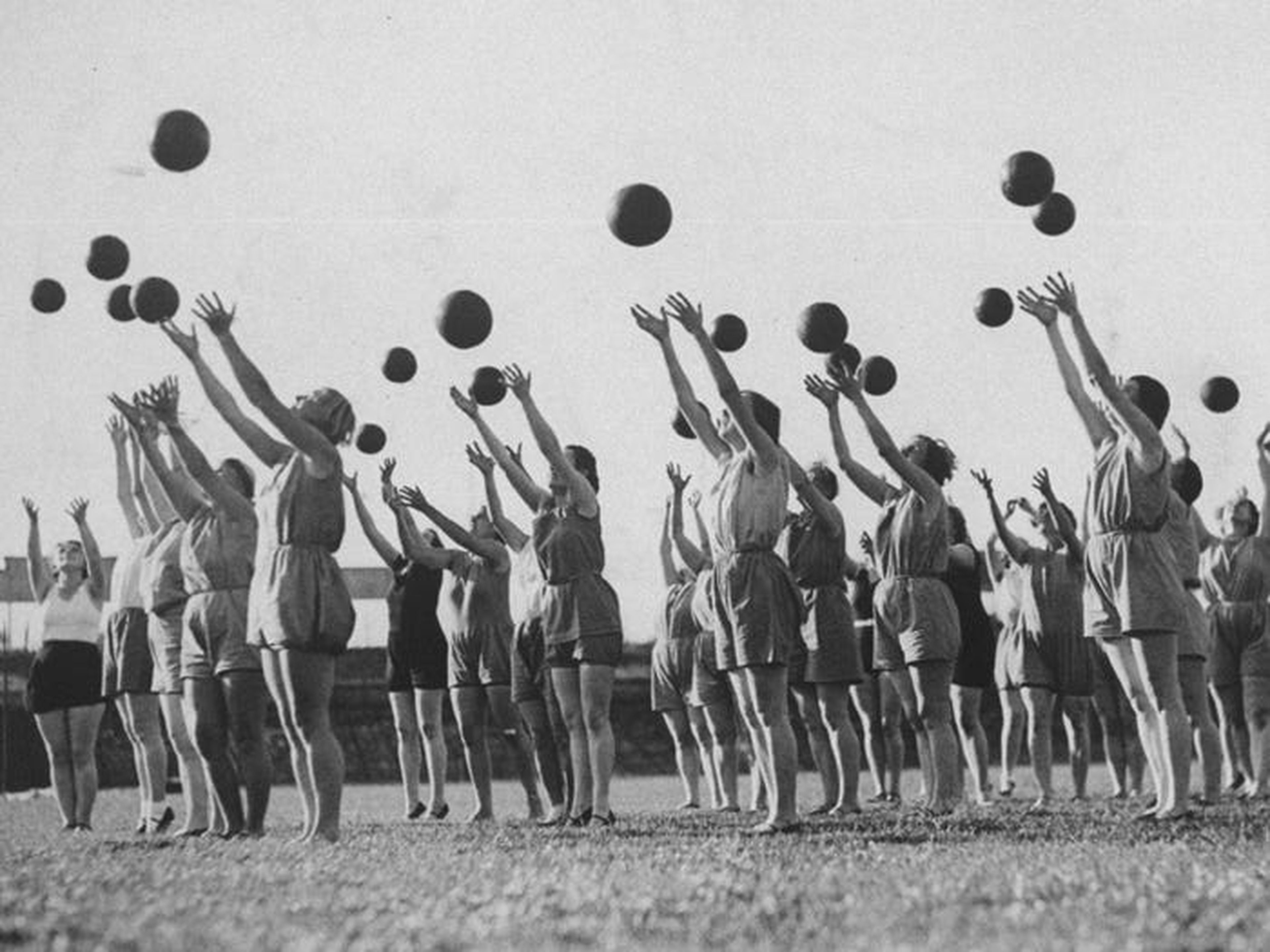 Gente lanzando pelotas sincronizadas en una clase de gimnasia de los años veinte.
