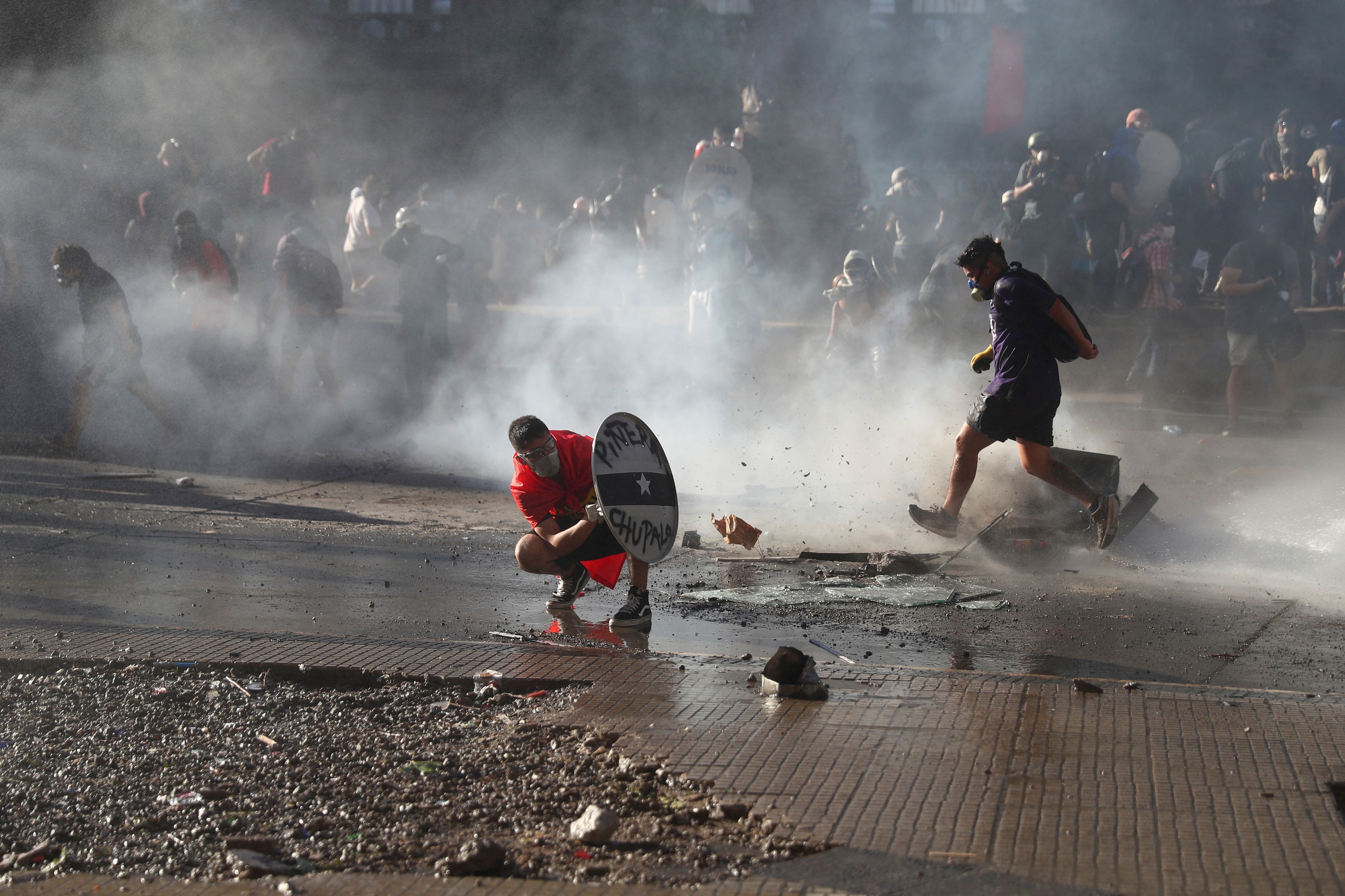 Manifestantes se cubren de la policía en Chile.