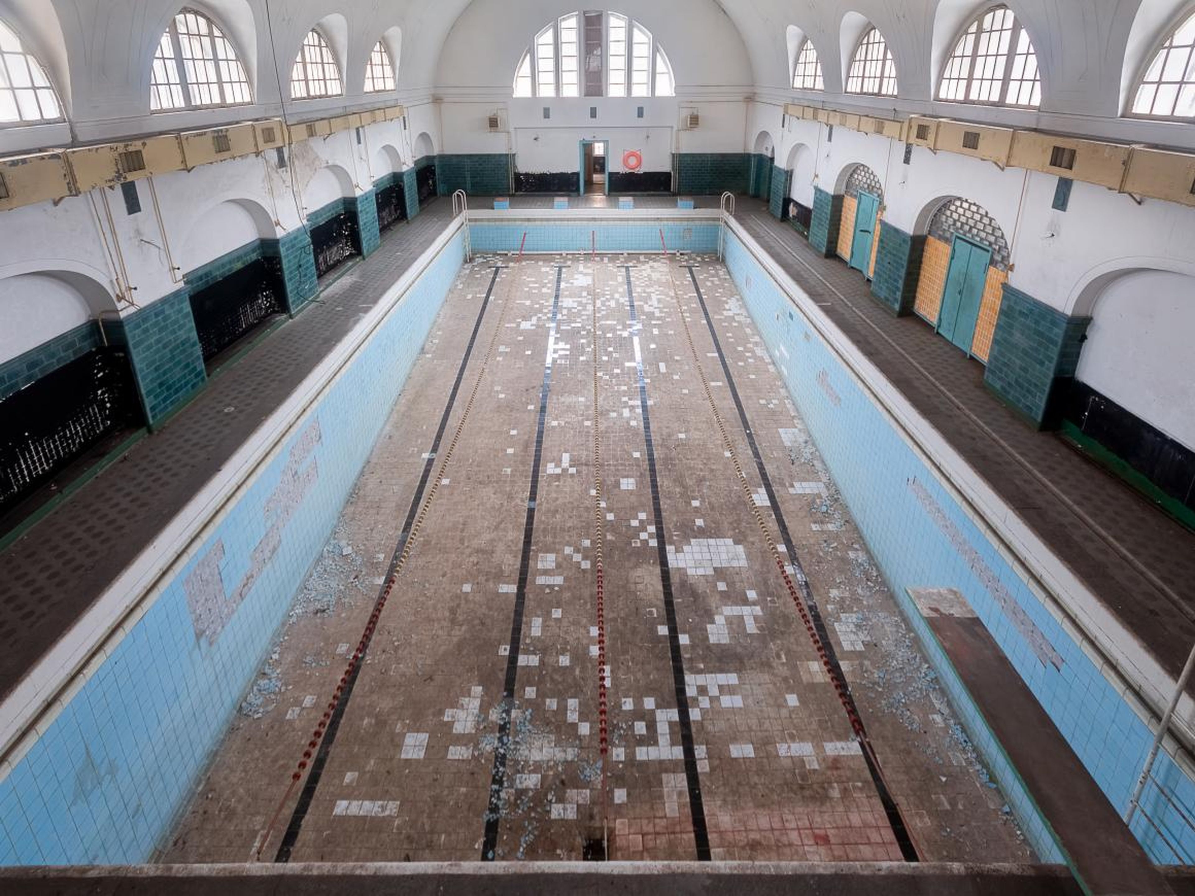 The swimming pool, completely empty of water, has remained frozen in time. You can see the lane dividers still hanging mid-air.