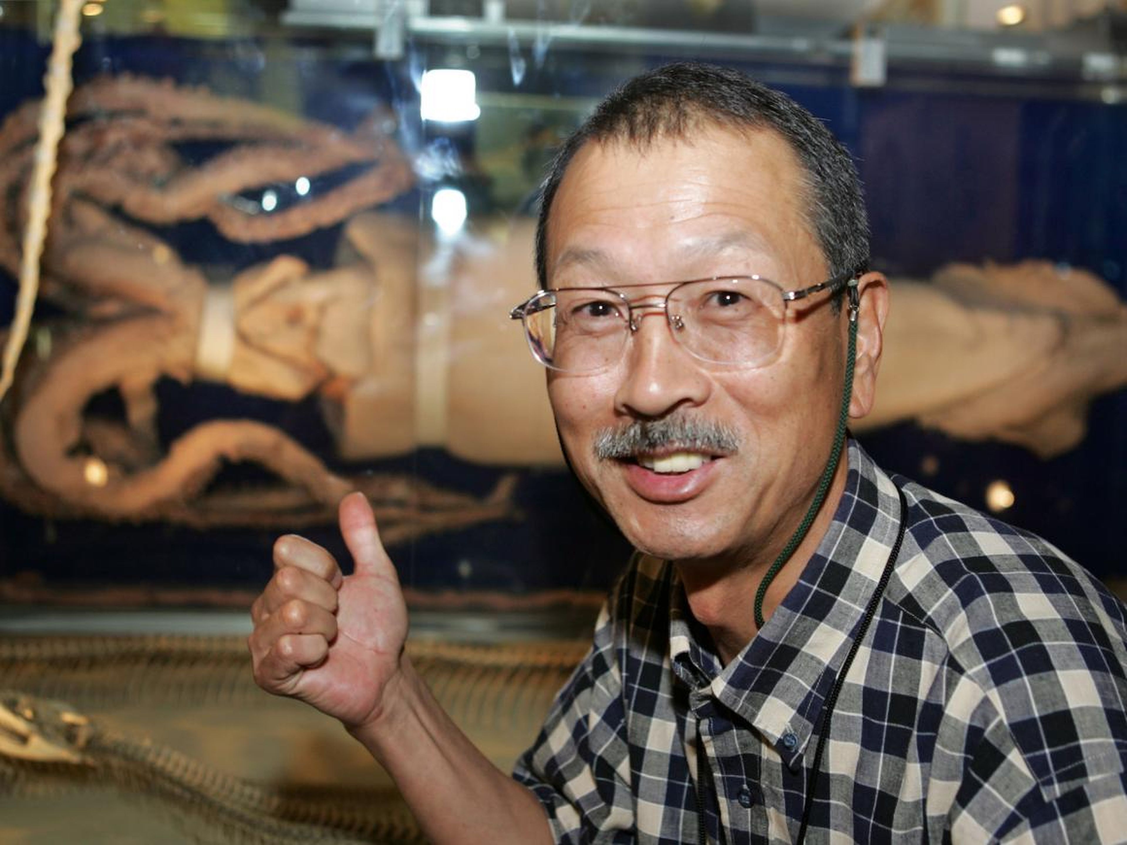 El investigador japonés Tsunemi Kubodera sonríe mientras muestra un calamar gigante en exhibición en el Museo Nacional de Ciencias en Tokio el 28 de septiembre de 2005.