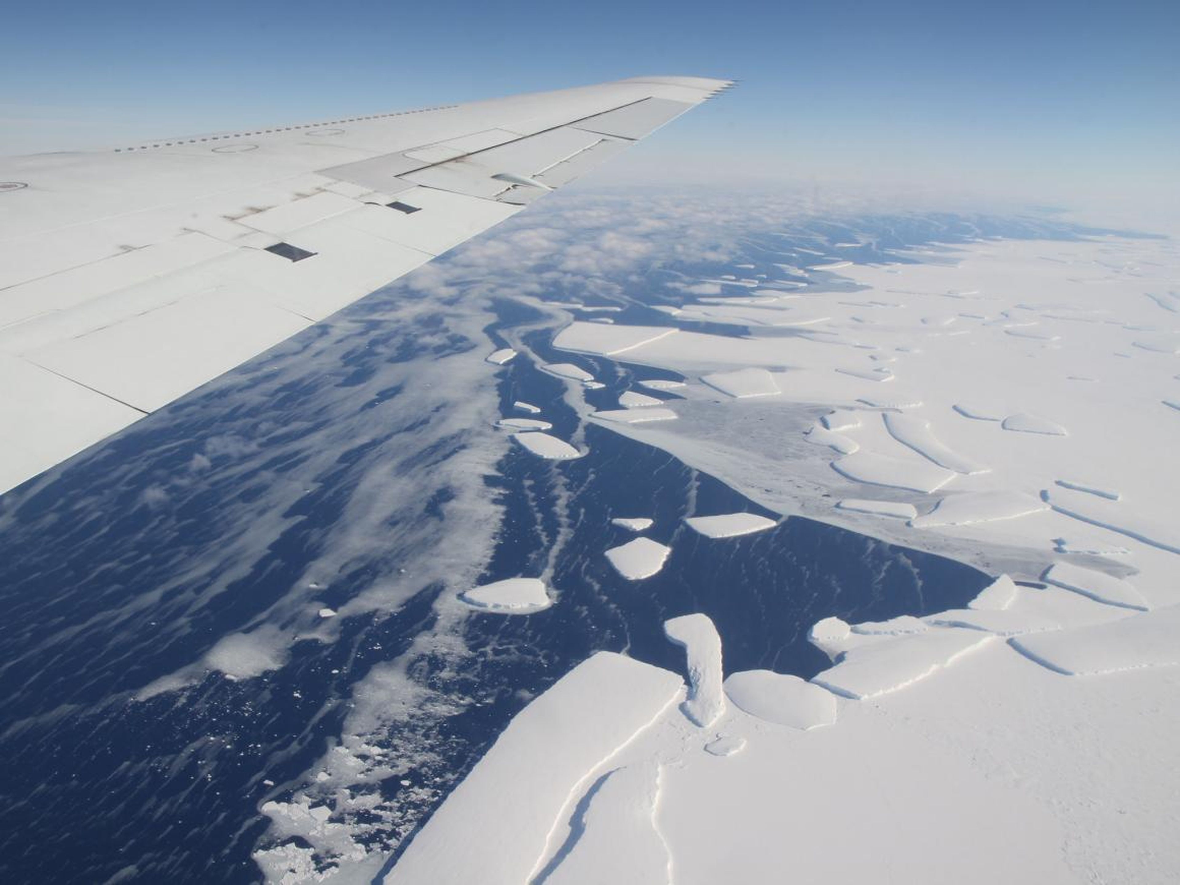 Una vista aérea de una plataforma de hielo en la Antártida occidental derramando icebergs.