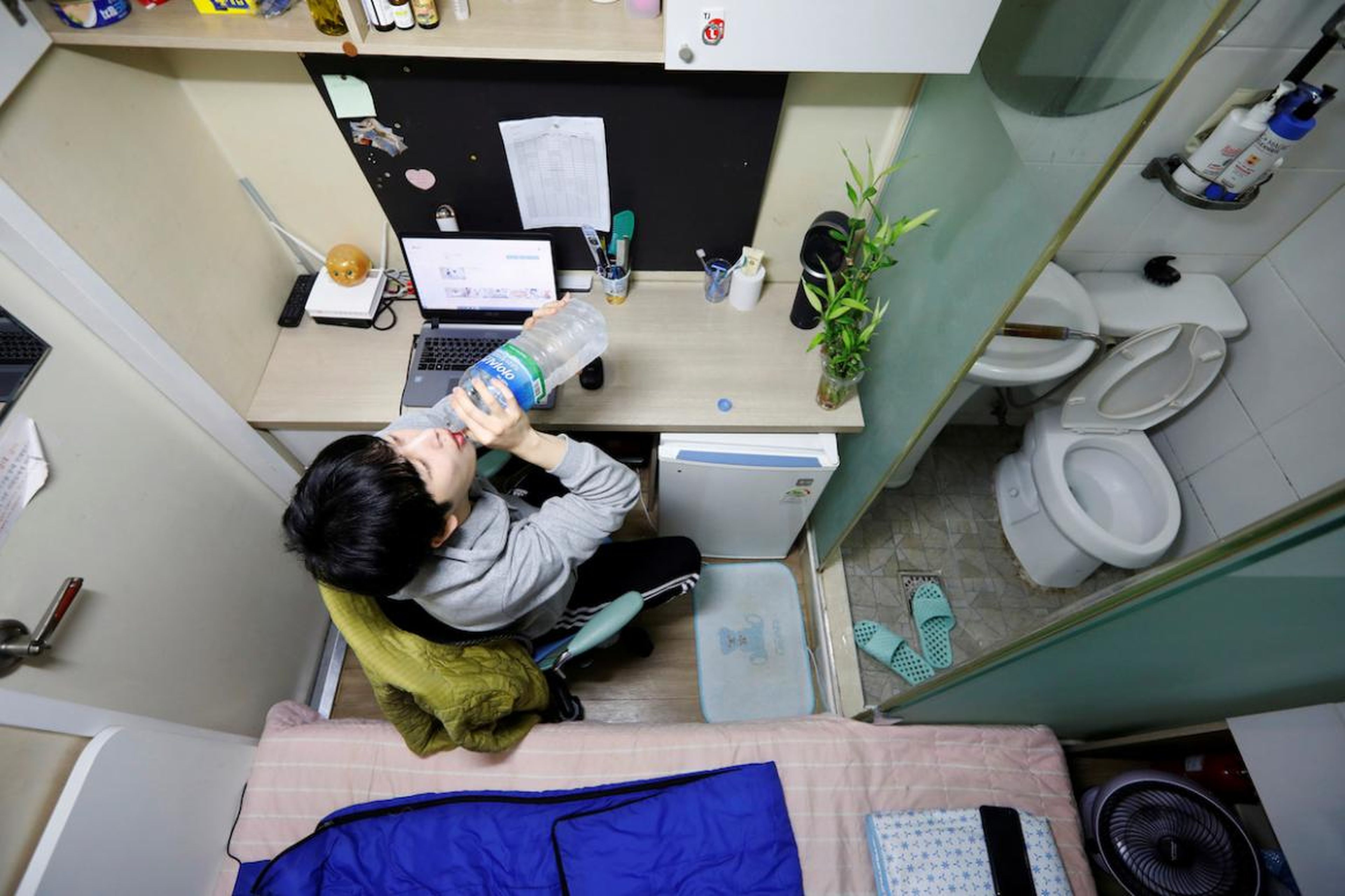 Kim Jae-hoon se sienta en un reducido cubículo llamado goshi-won, donde vive, en Suwon, Corea del Sur, en noviembre.