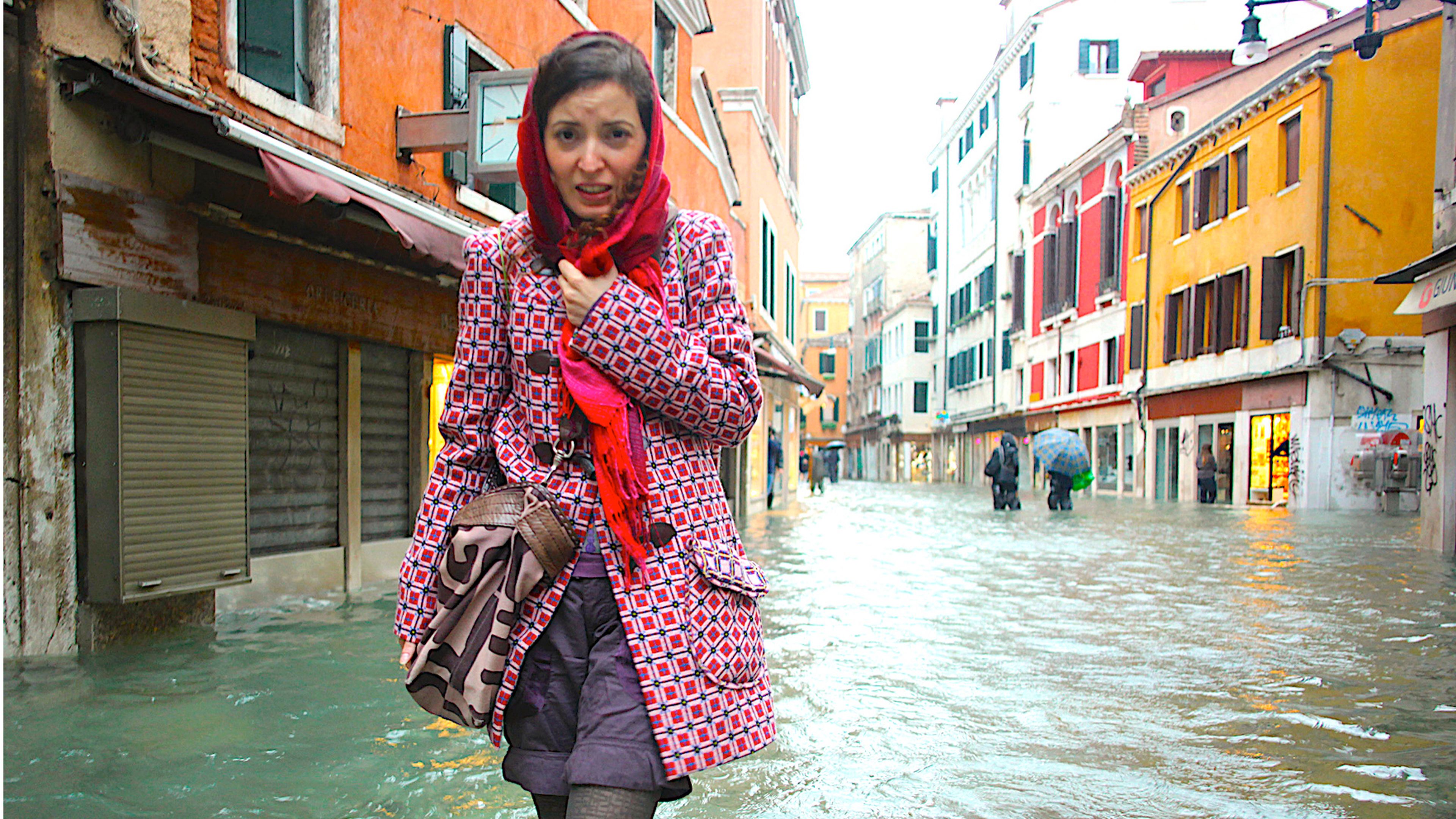 Una mujer camina por una calle inundada durante el periodo de marea alta en Venecia, Italia