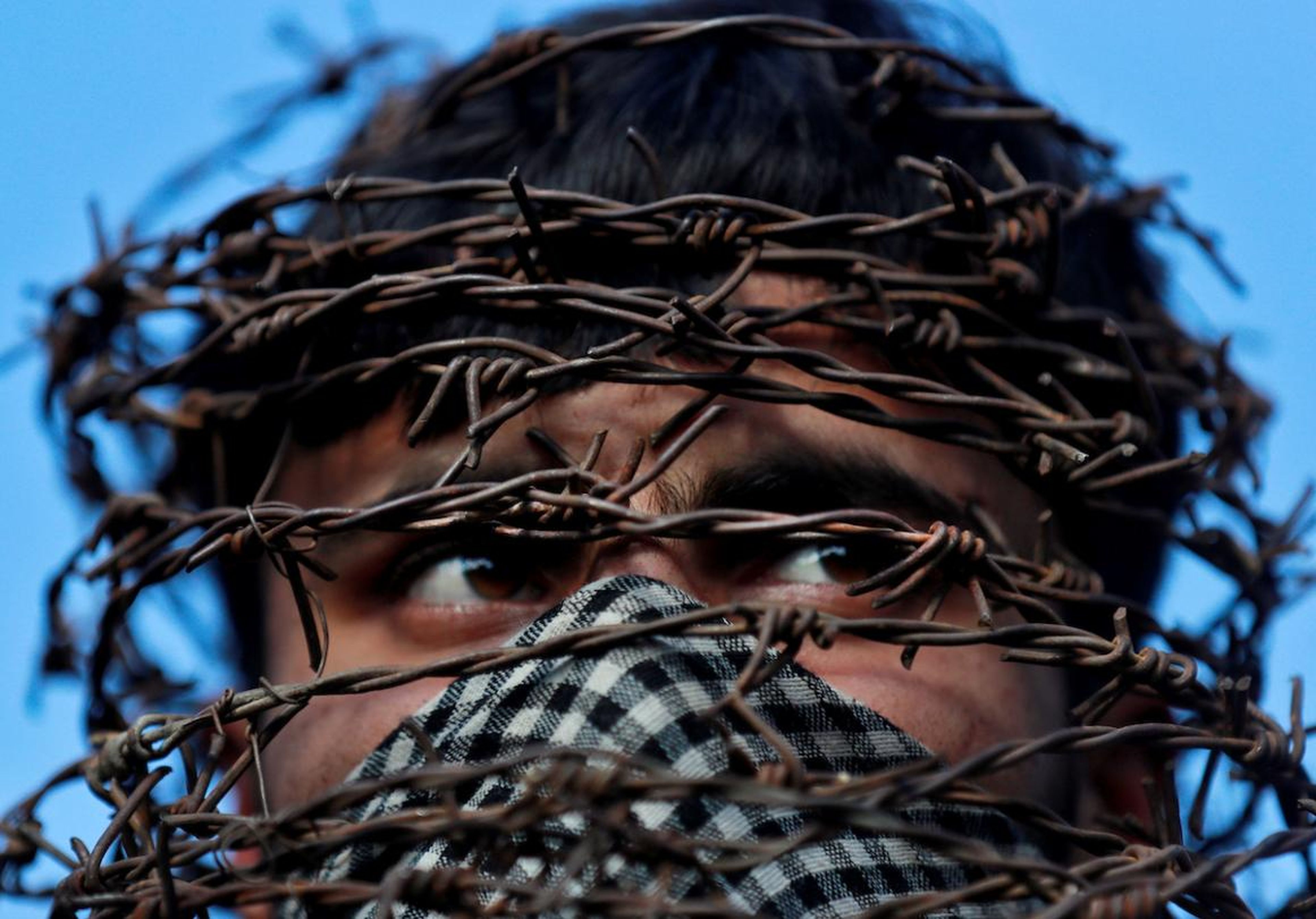 On October 11, a masked Kashmiri man with his head covered with barbed wire attends a protest after Friday prayers during restrictions following the Indian government's scrapping of the special constitutional status for Kashmir in