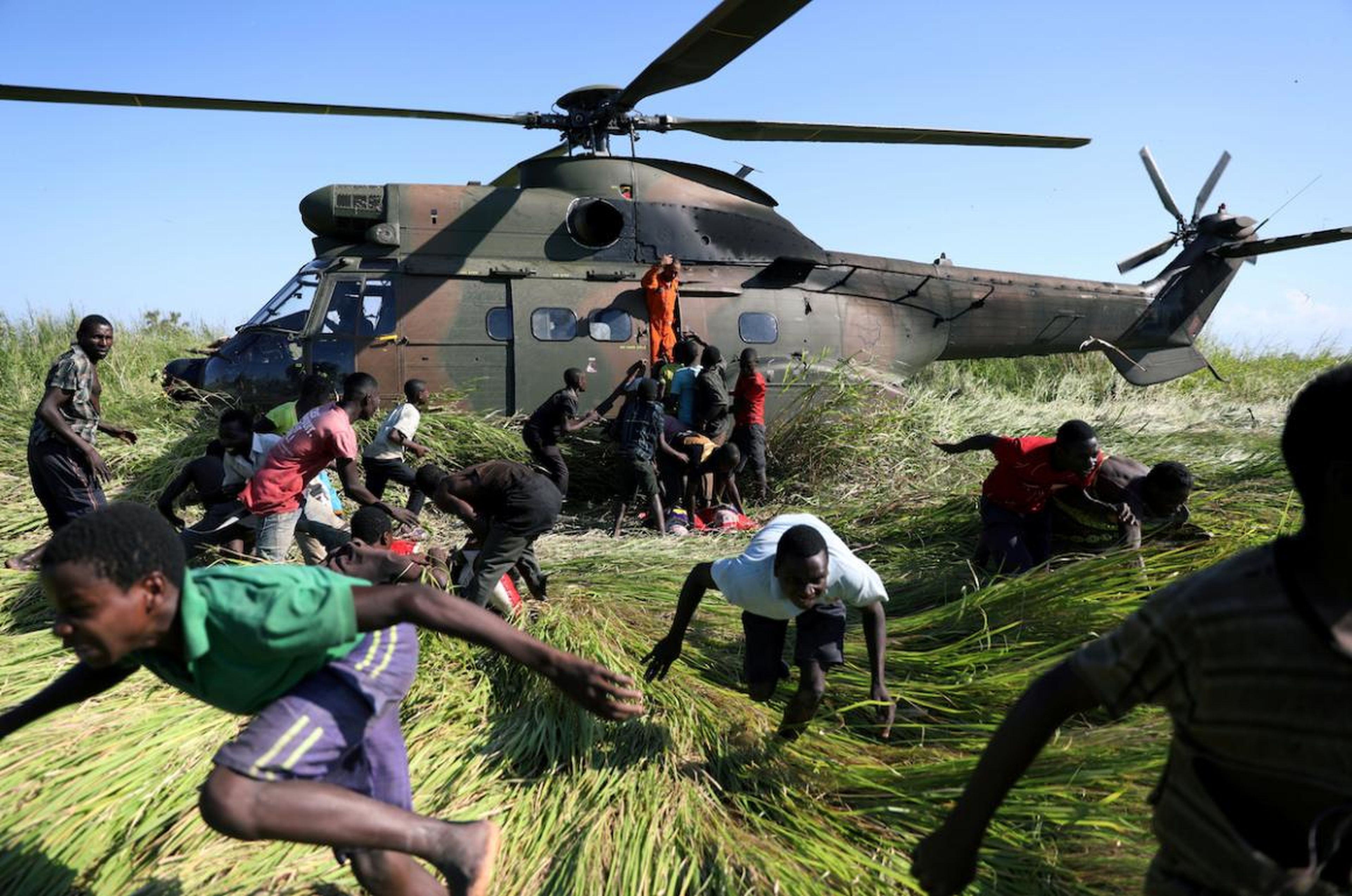 Varias personas huyen tras recoger ayuda alimentaria de un helicóptero de la Fuerza de Defensa Nacional de Sudáfrica (SANDF) tras el ciclón Idai en la aldea de Nhamatanda, cerca de Beira, Mozambique, en marzo.