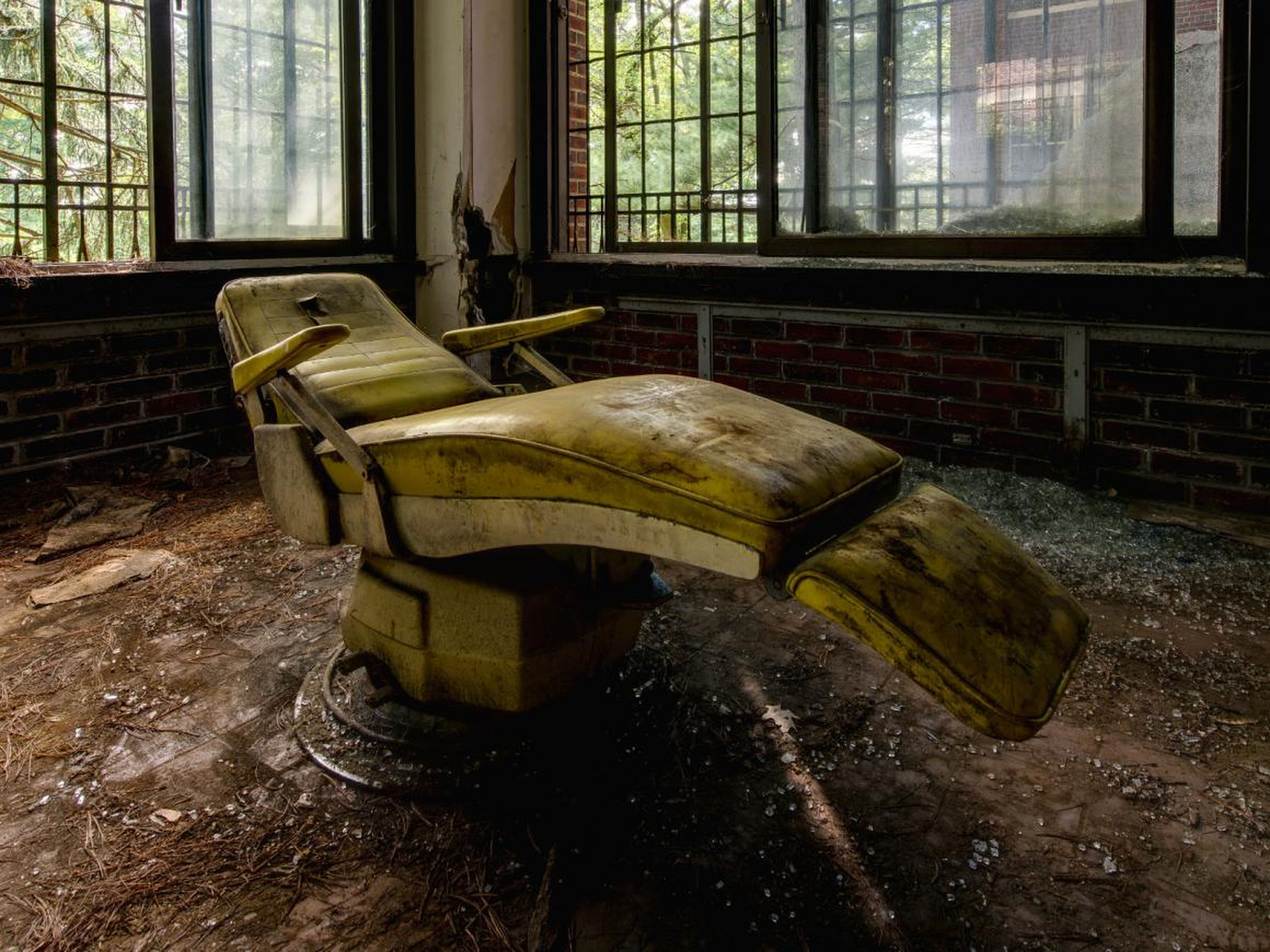 Espeluznante silla de paciente dentro de un hospital psiquiátrico abandonado.
