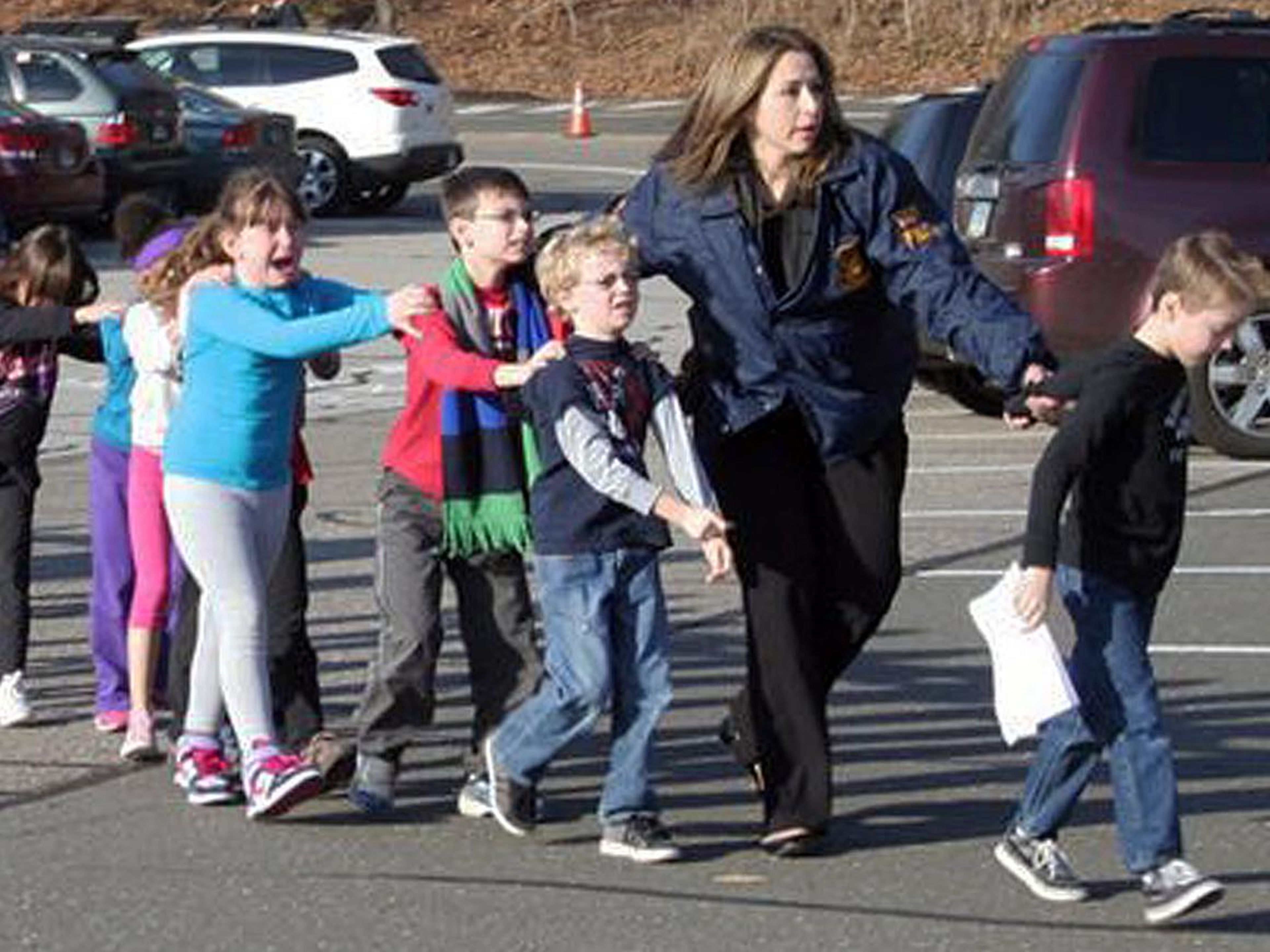 Una oficial de policía conduce a niños de la escuela primaria Sandy Hook.