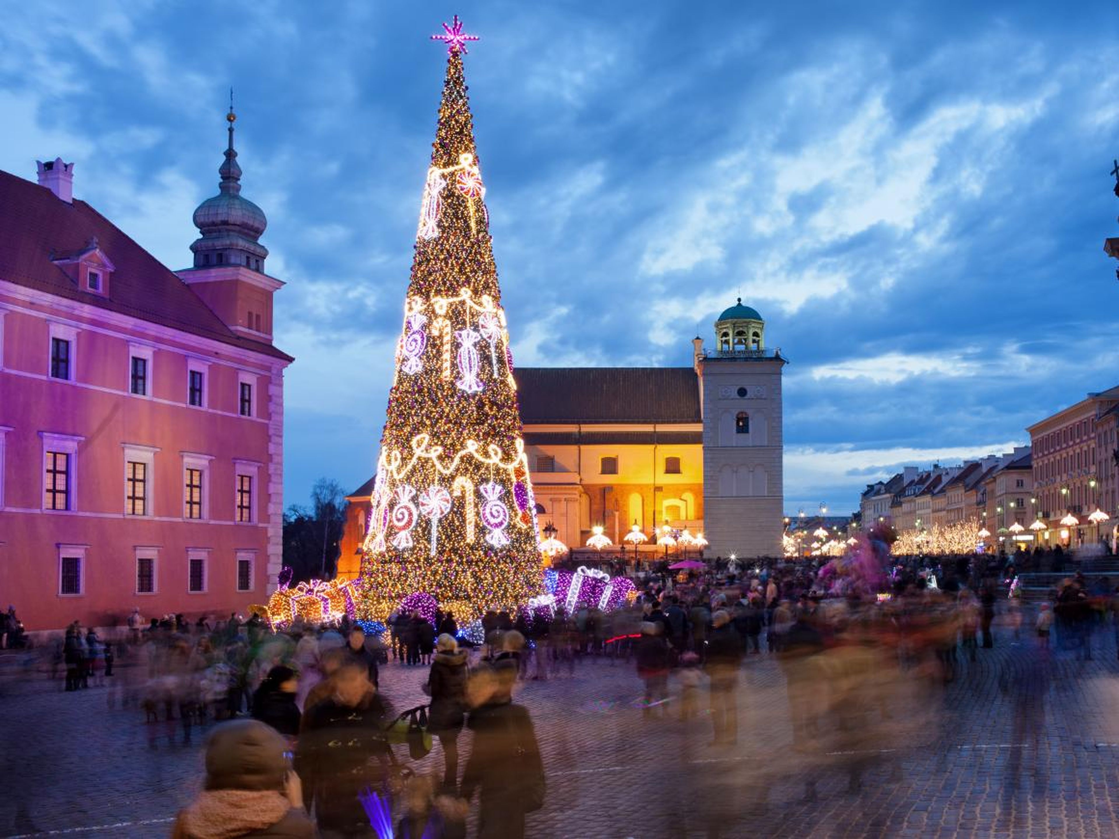 Árbol de Navidad y la gente en la Plaza del Castillo en el casco antiguo de Varsovia, Polonia, iluminada al atardecer.