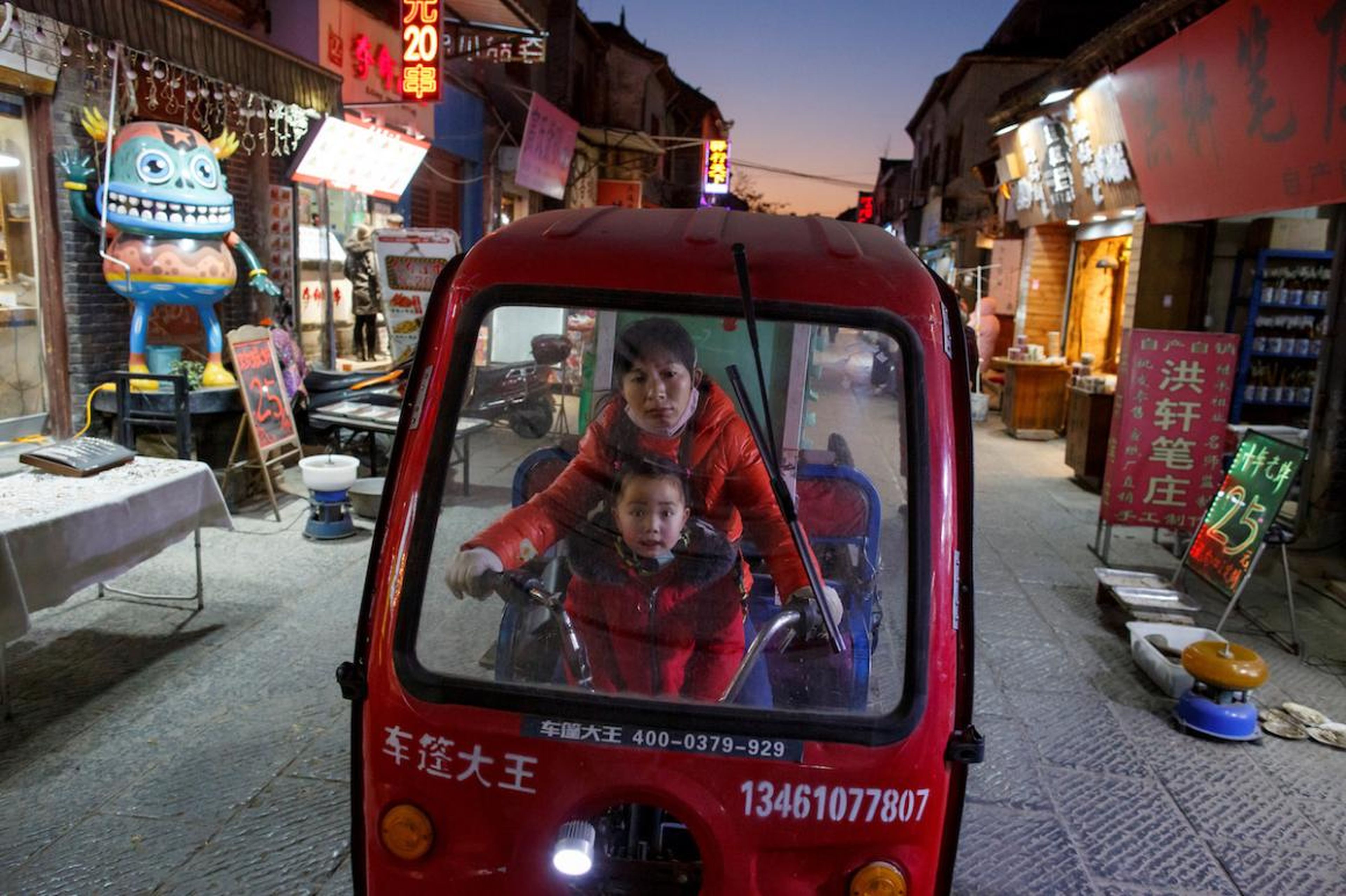 Una mujer y un niño montan un triciclo eléctrico en el casco antiguo de Luoyang, provincia de Henan, China, en enero.