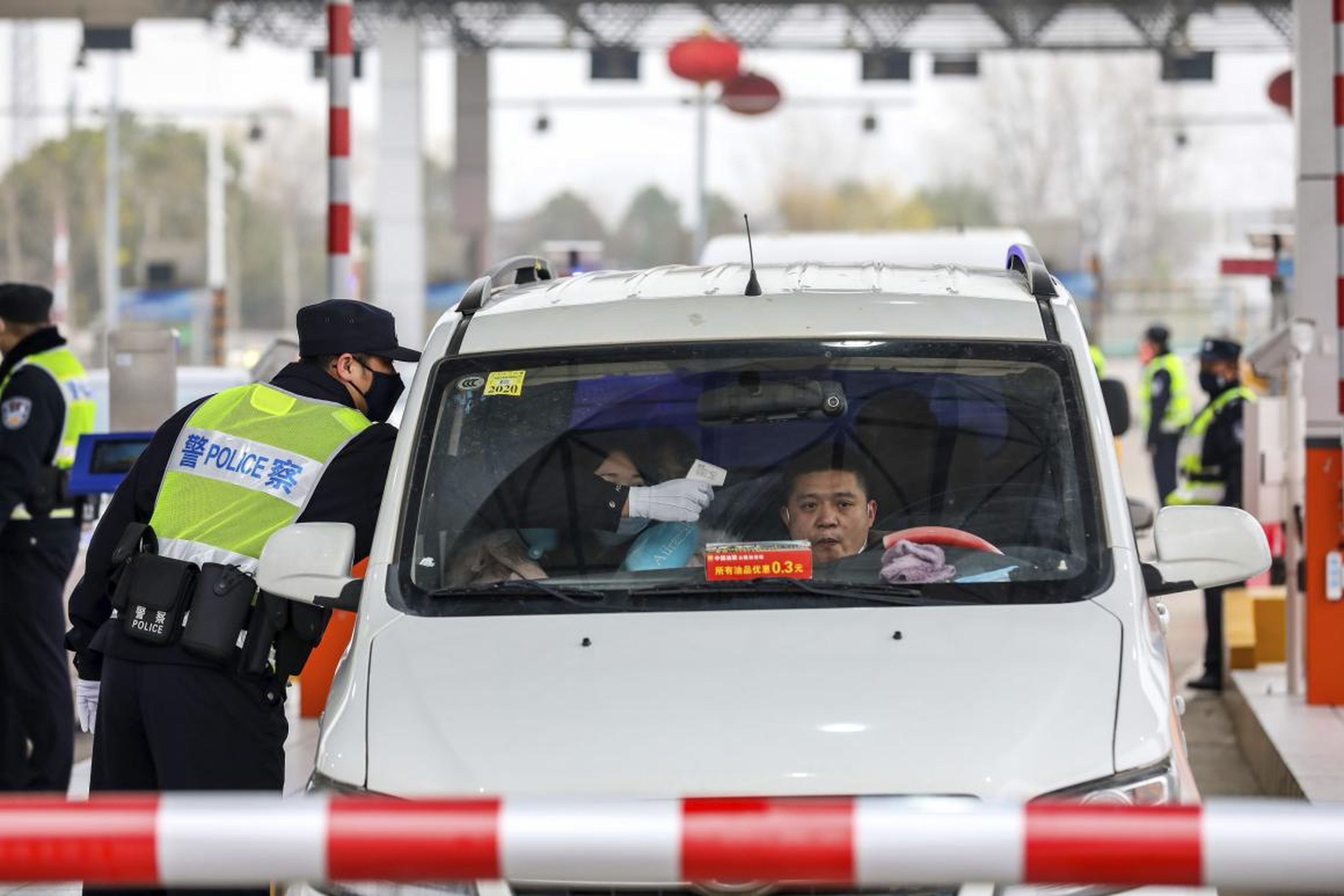 A policeman uses a digital thermometer to take a driver's temperature at a checkpoint at a highway toll gate in Wuhan, China on January 23, 2020.