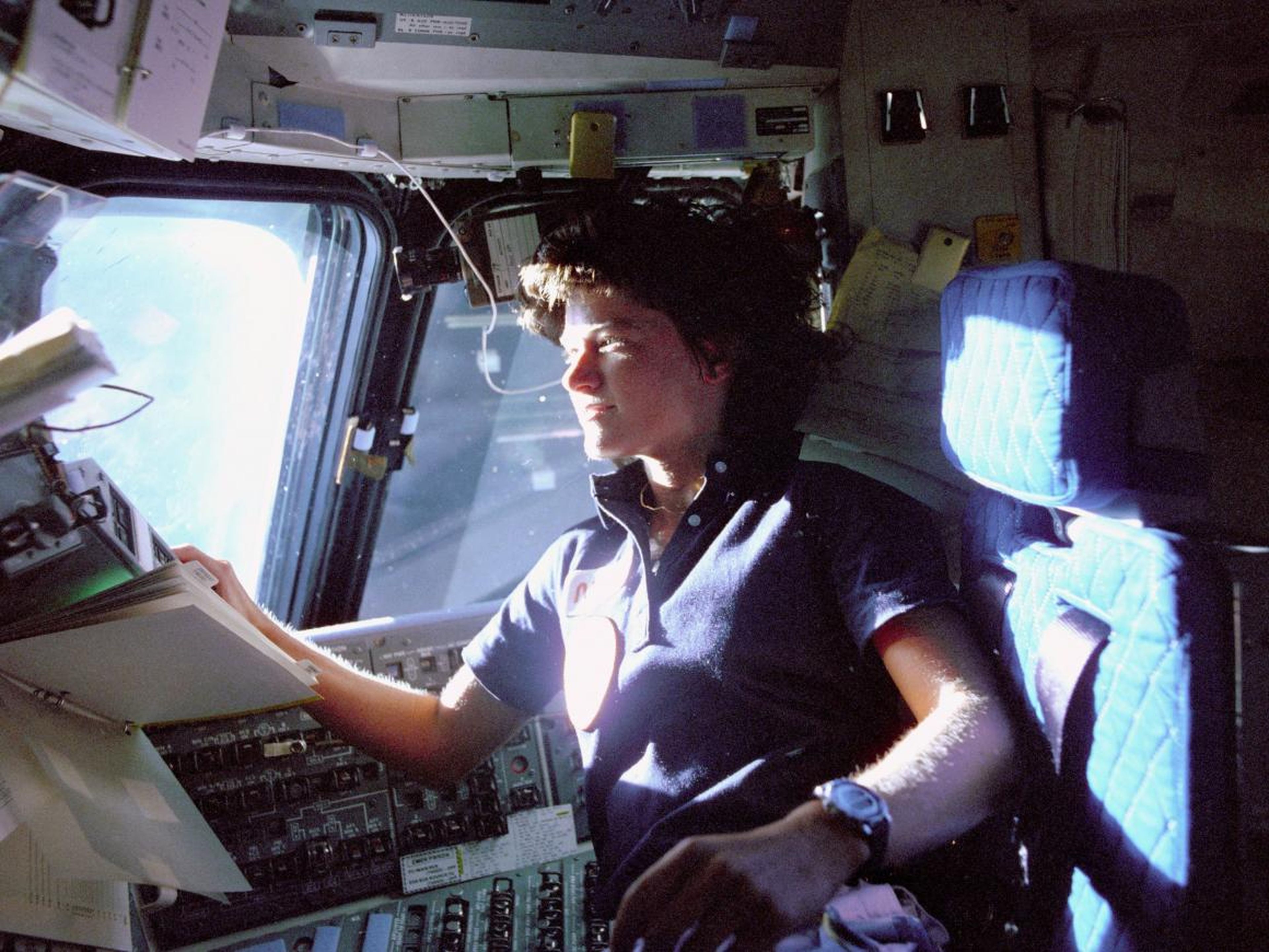 Sally Ride, la primera astronauta estadounidense en el espacio, monitoriza los paneles de control desde la cubierta de vuelo.