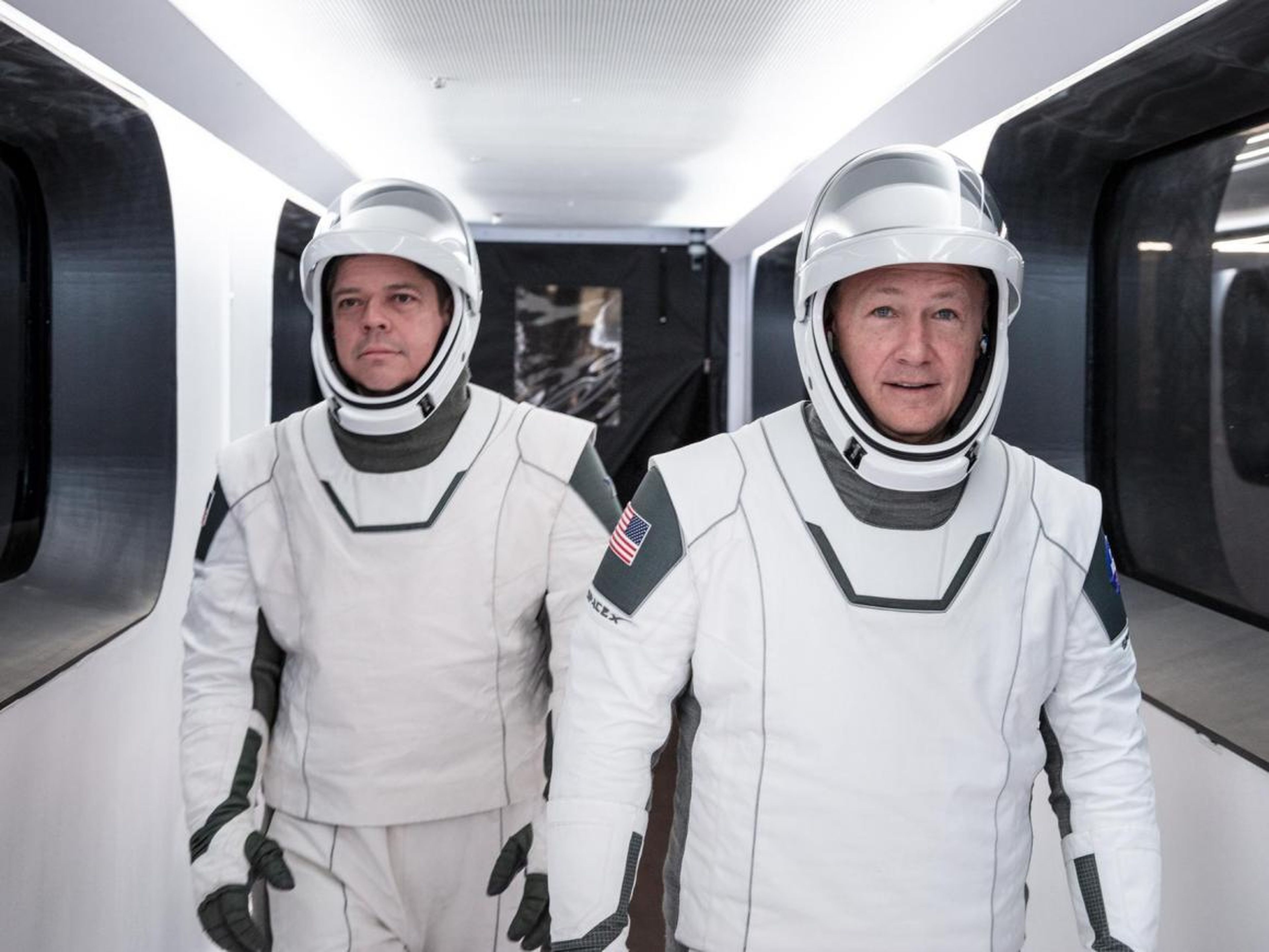 Behnken (izquierda) y Hurley (derecha) con los trajes espaciales de Space X caminando hacia la torre de lanzamiento de la nave espacial Crew Dragon.