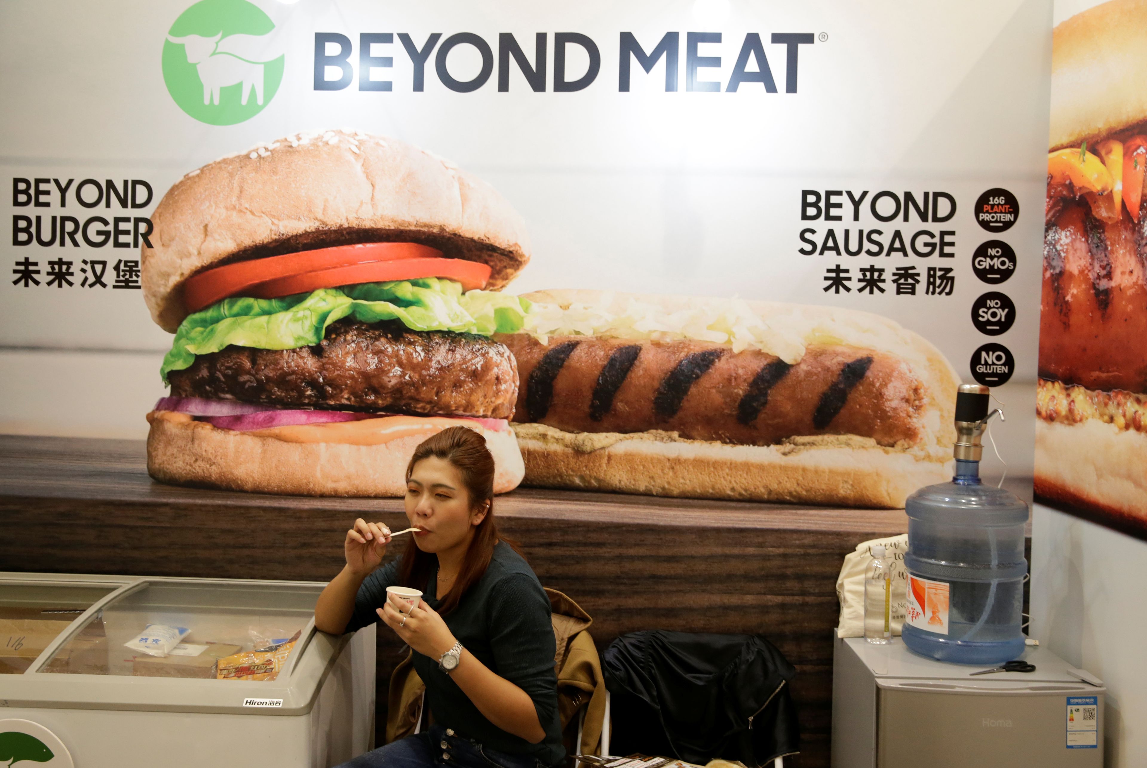 Una mujer junto a un póster del stand de la compañía de alimentos a base de plantas Beyond Meat en la feria VeggieWorld de Pekín.