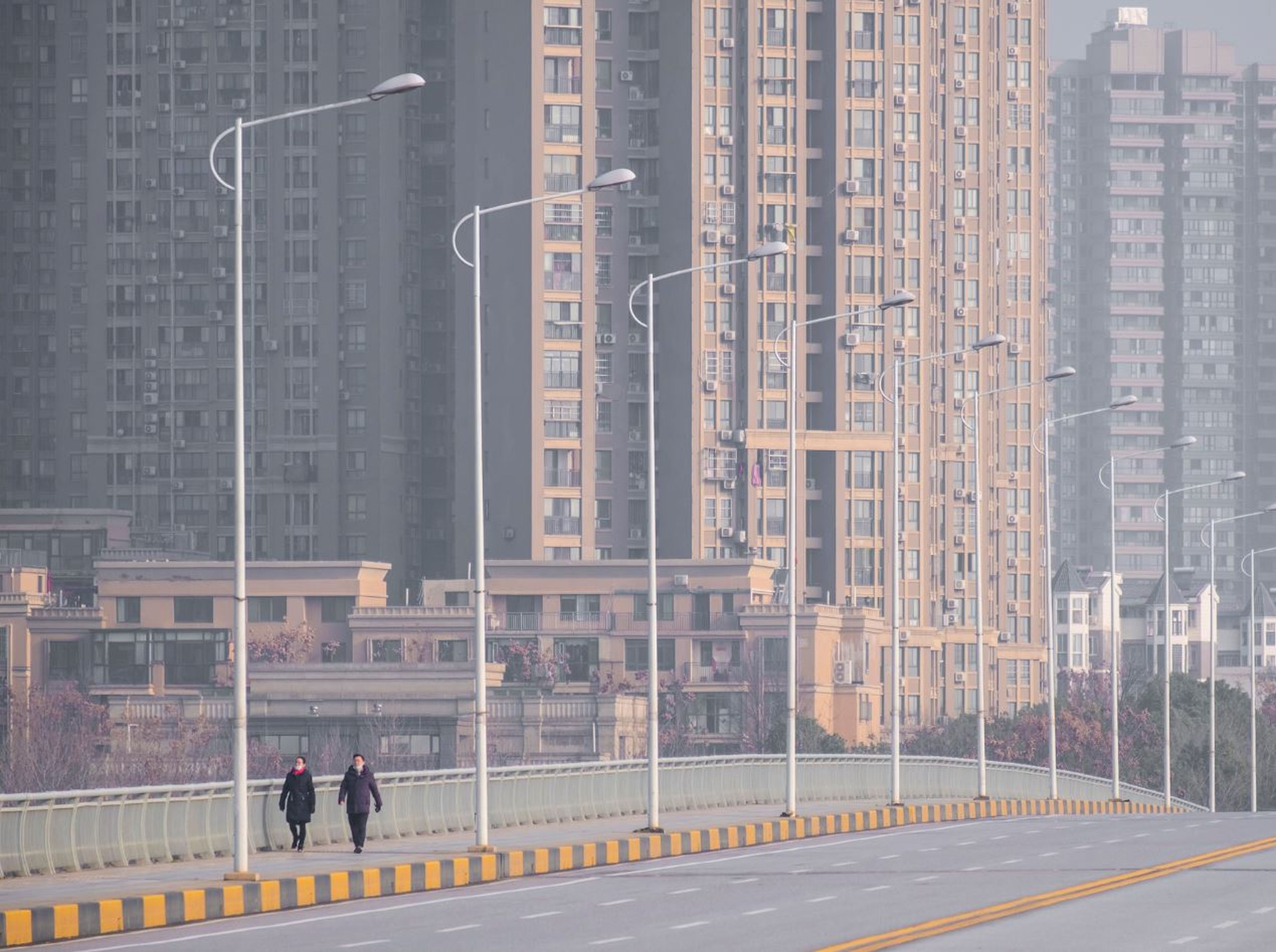 Dos personas caminan por la calle en Wuhan portando máscaras protectoras.