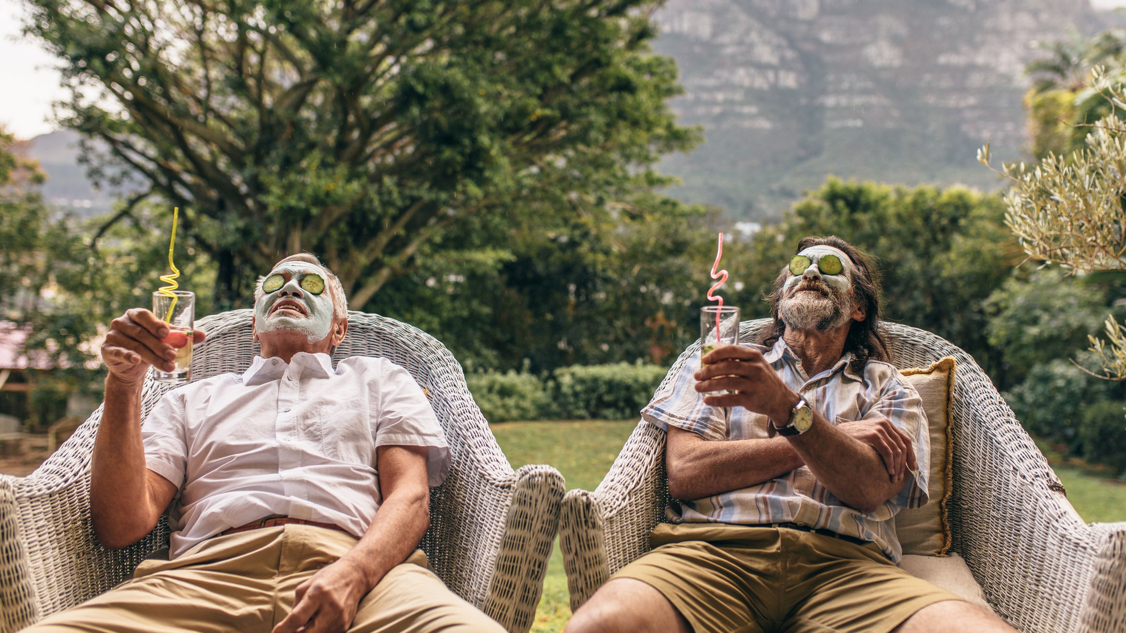 Dos hombres adultos, casi jubilados, relajados tomando un te mientras tienen una mascarilla en la cara