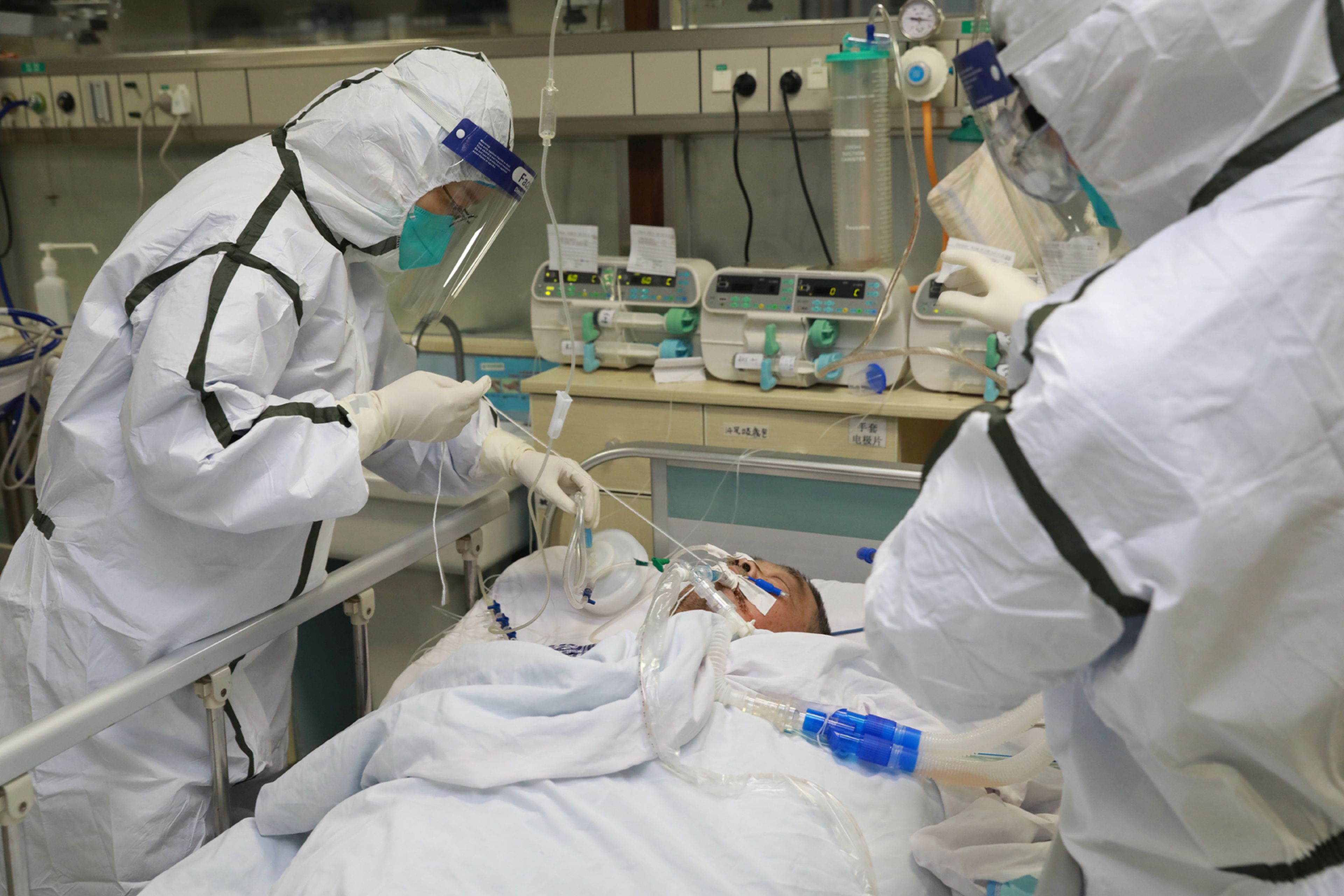 Dos médicos vestidos con trajes protectores tratan a un paciente en un hospital de Wuhan