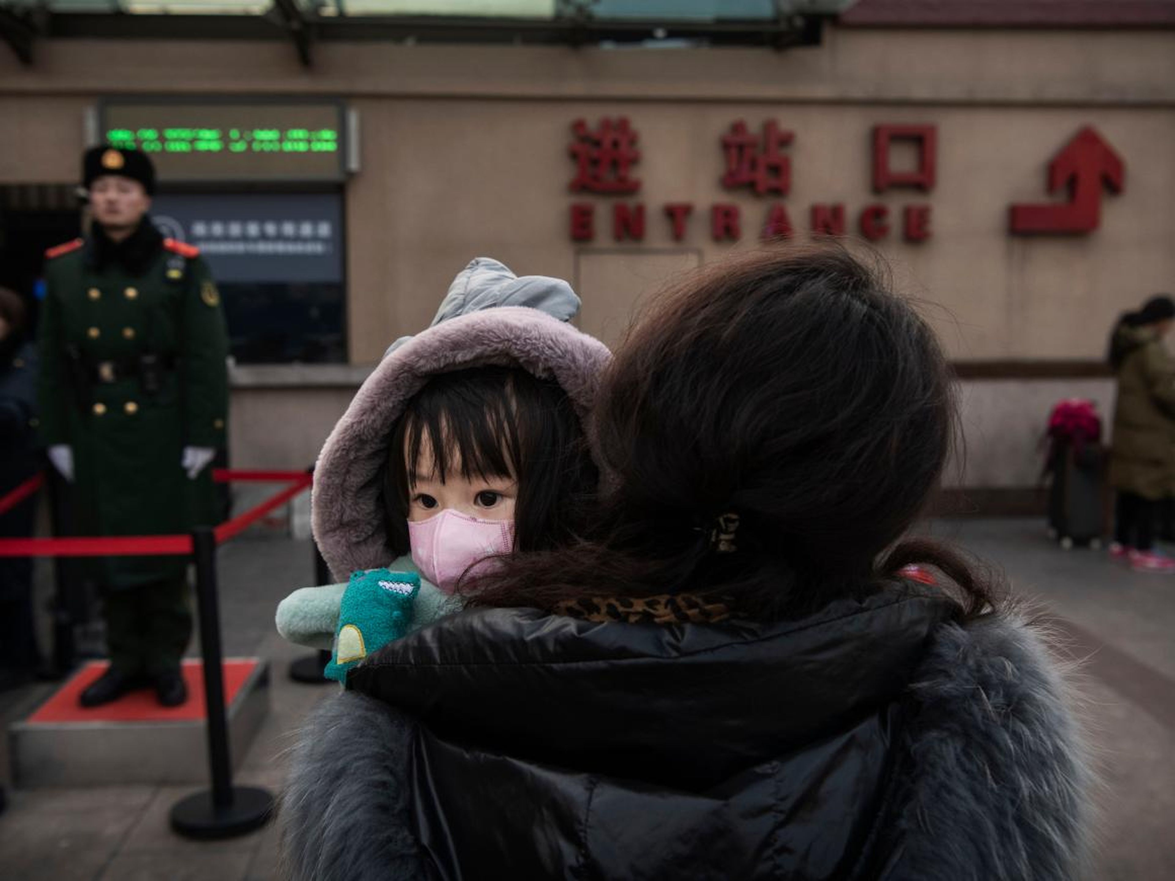 Una niña con una mascarilla en una estación de tren de Pekín.