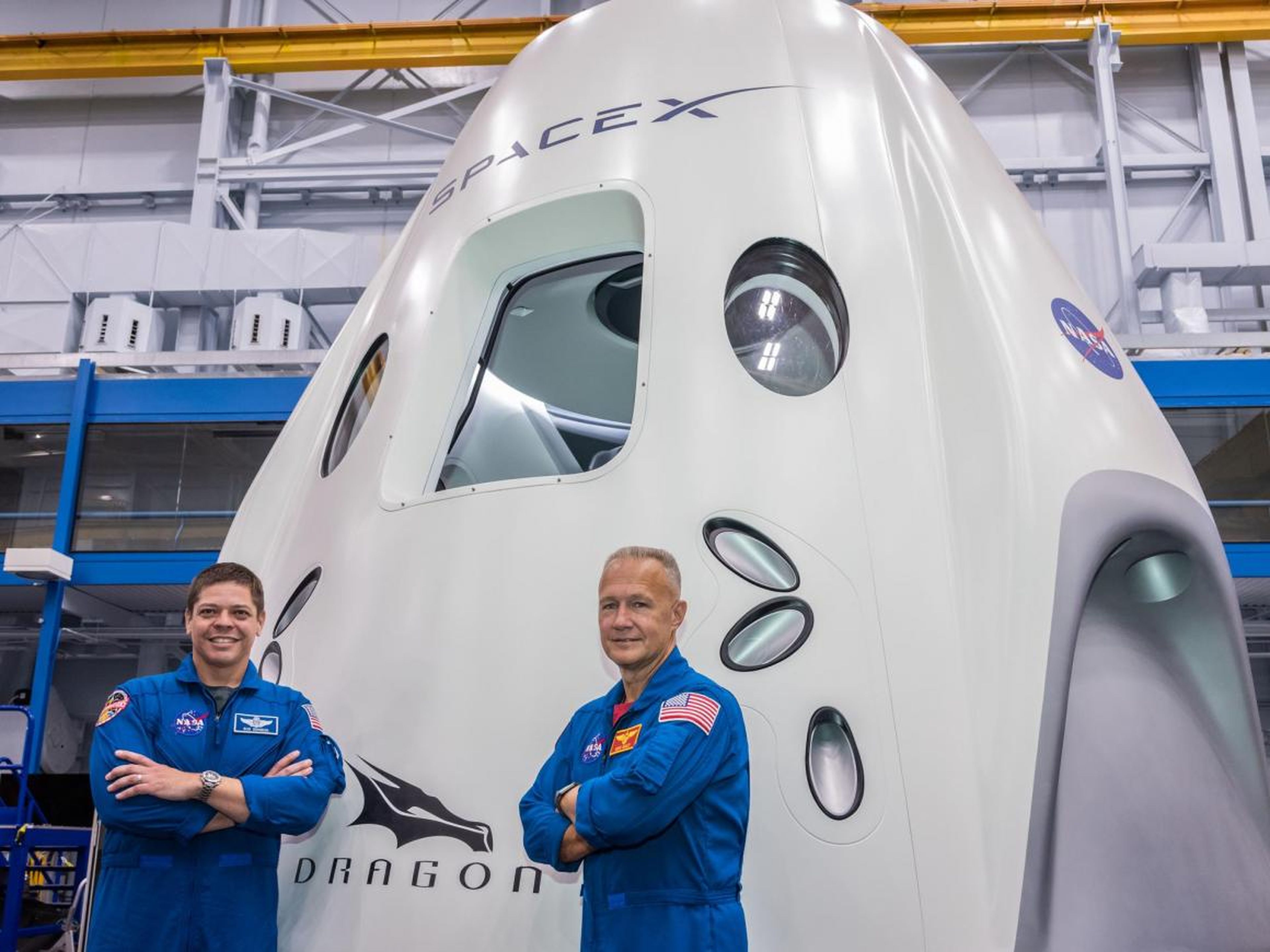 Behnken (izquierda) y Hurley (derecha) posando frente a la maqueta de la nave Dragon de SpaceX en el Centro Espacial Johnson de la NASA.